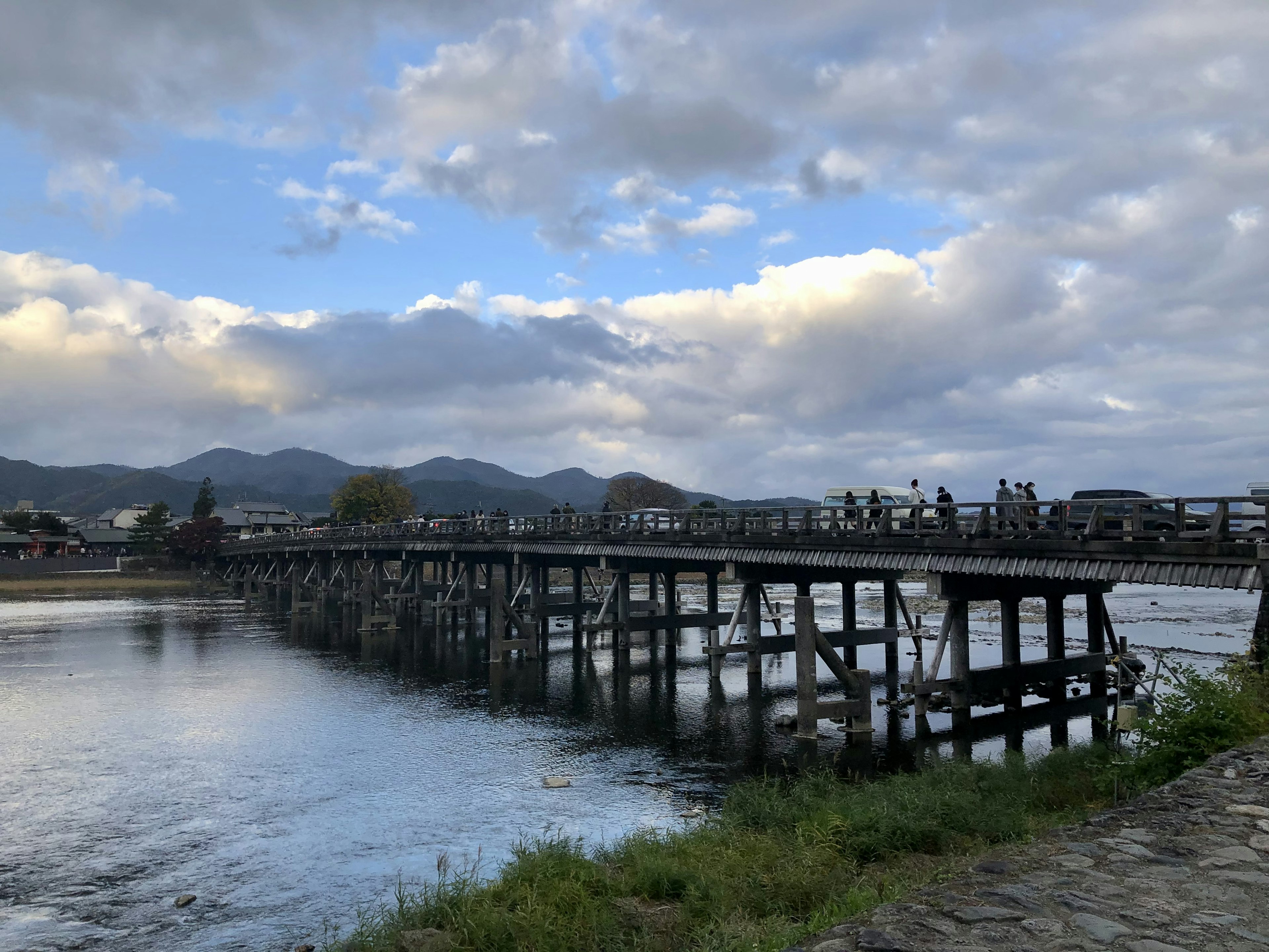 一座木橋橫跨河流，藍天和雲朵為背景