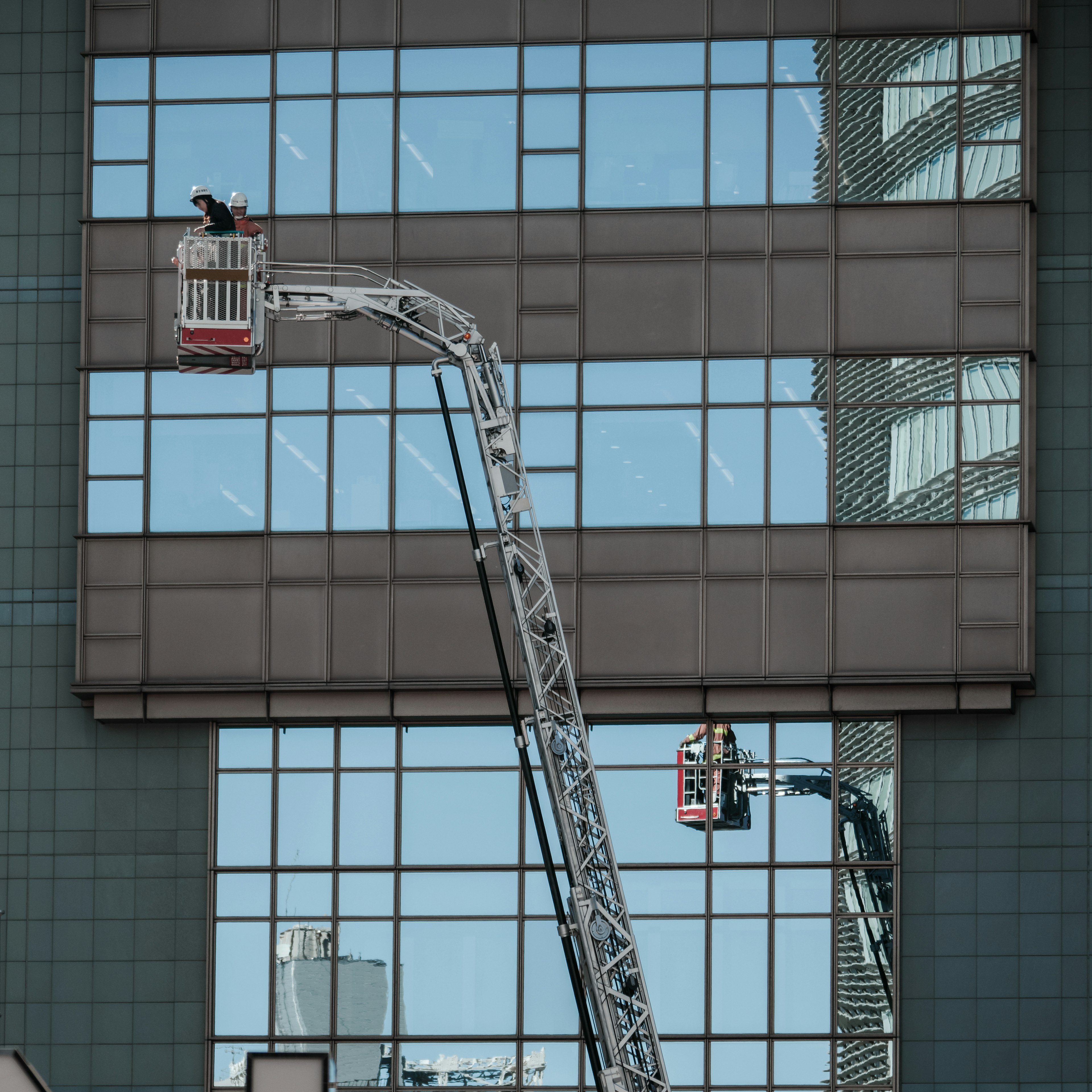 Workers cleaning windows of a high-rise building using a lift