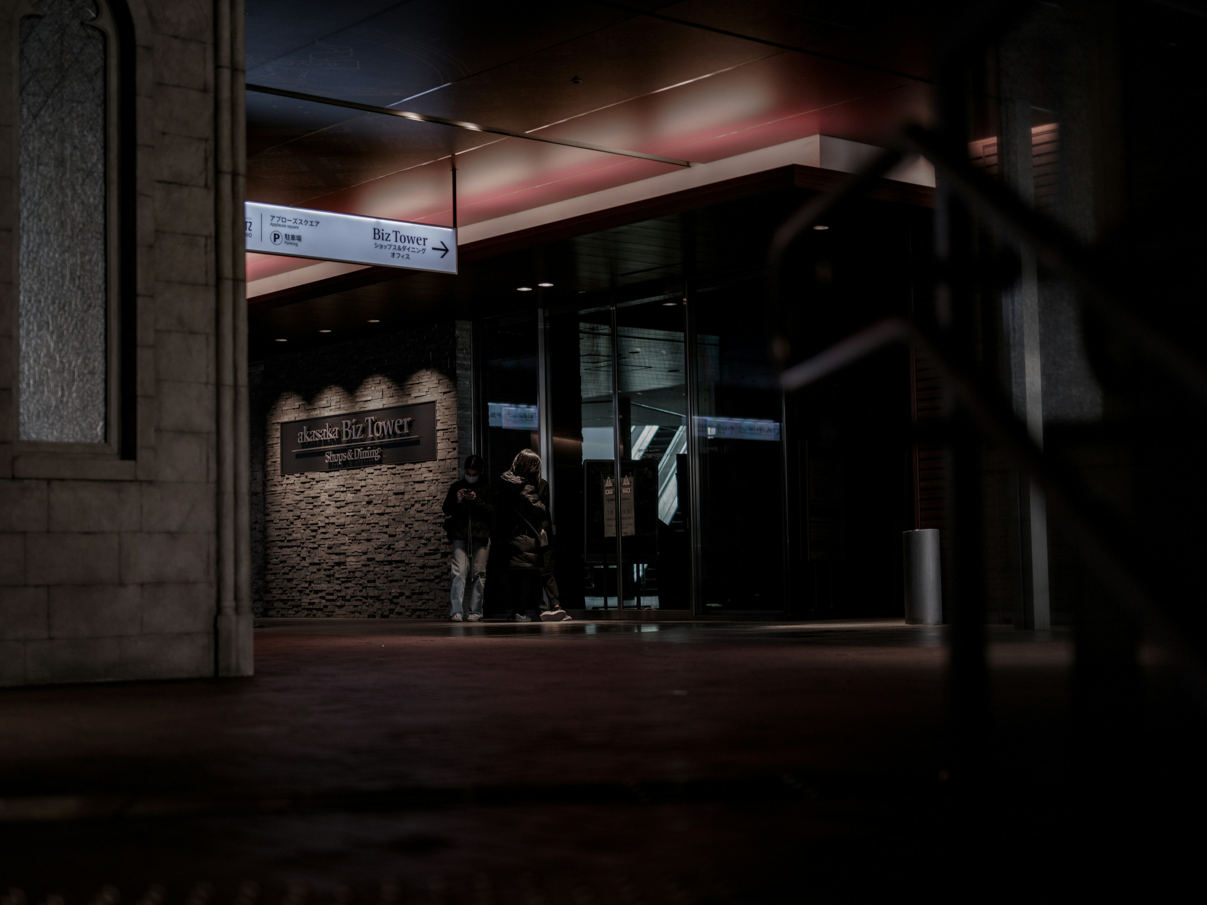 Entrée d'un bâtiment moderne dans une rue sombre avec des gens rassemblés