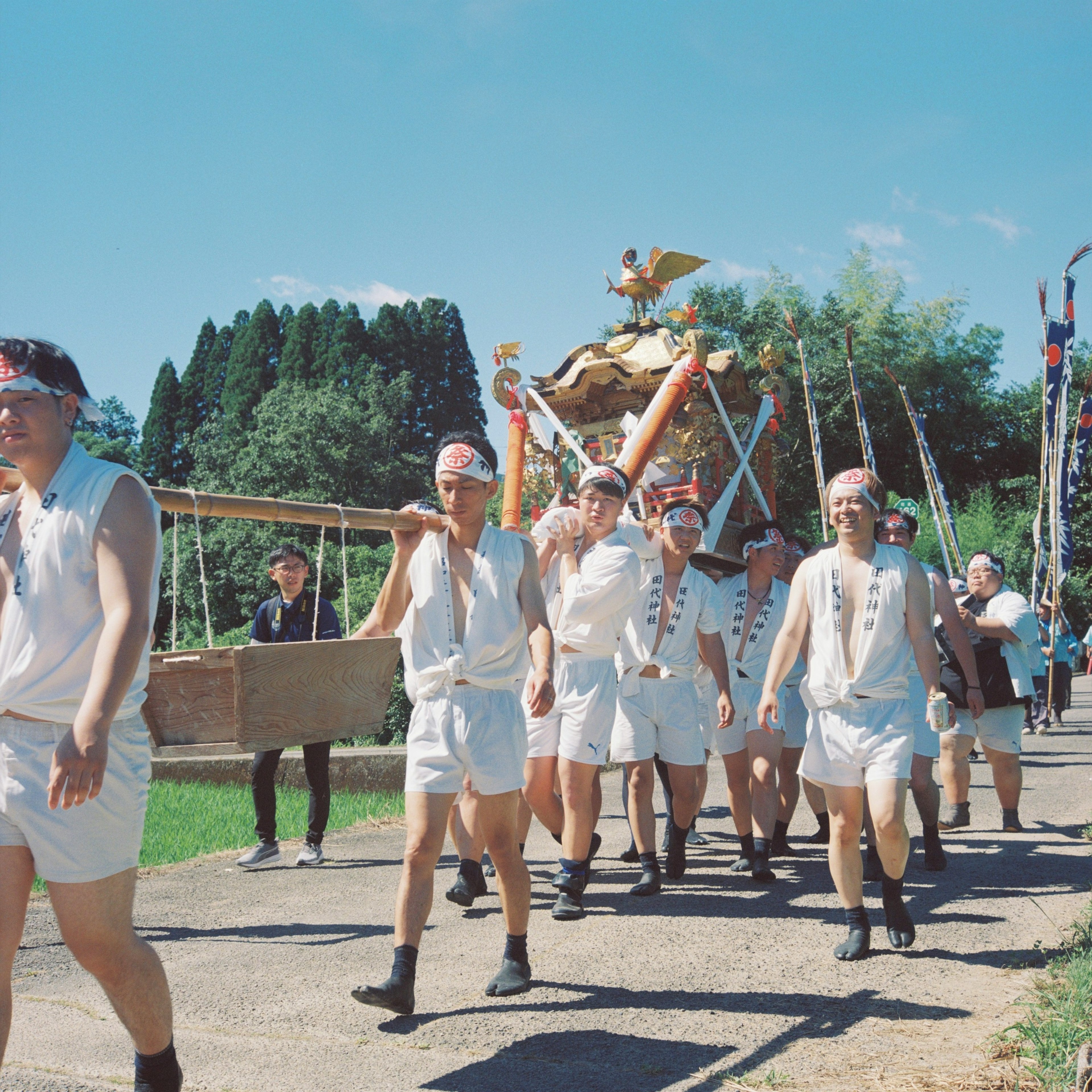 祭りのために衣装を着た男性たちが行進している風景