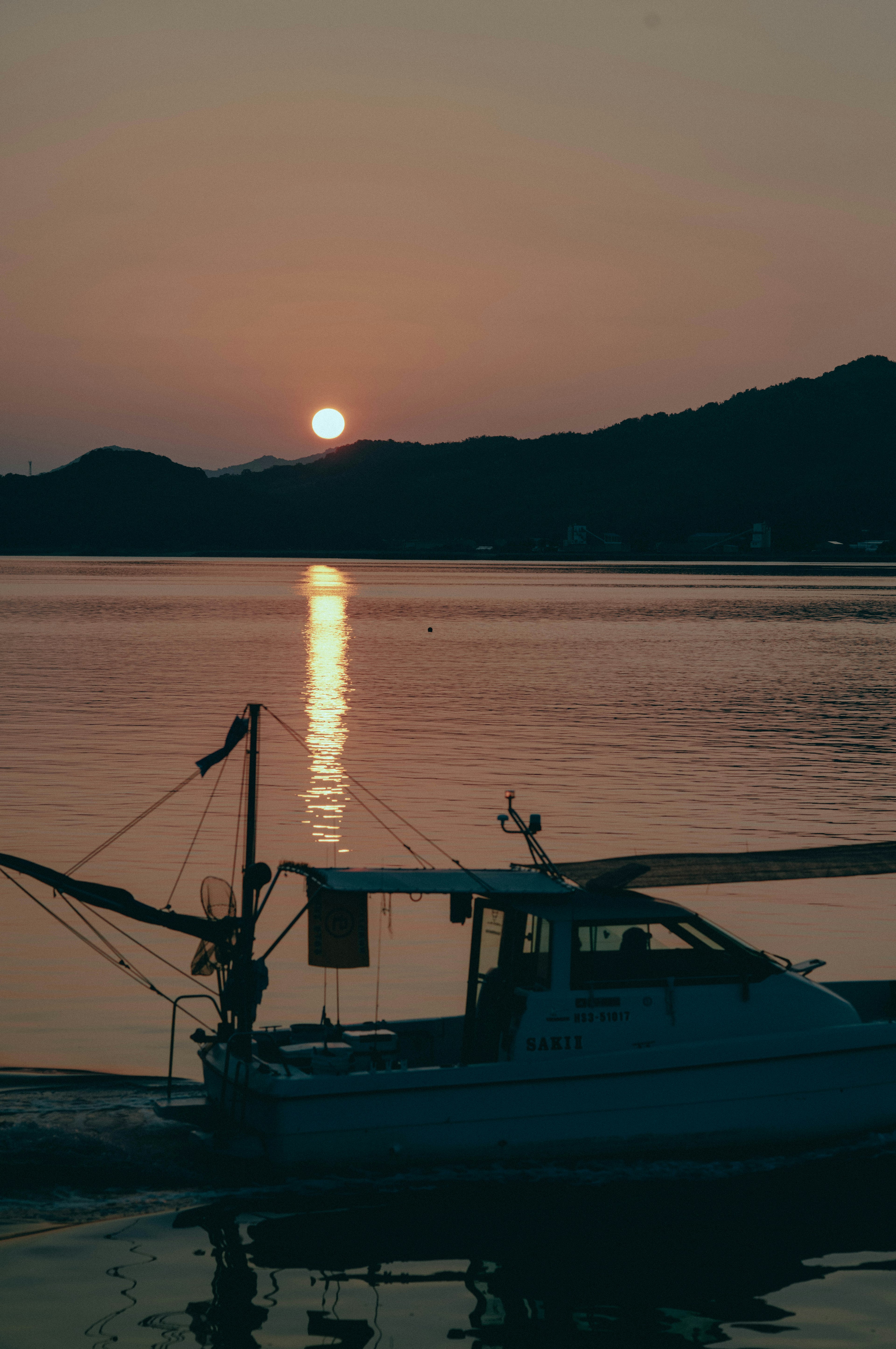 夕日が反射する水面と漁船のシルエット