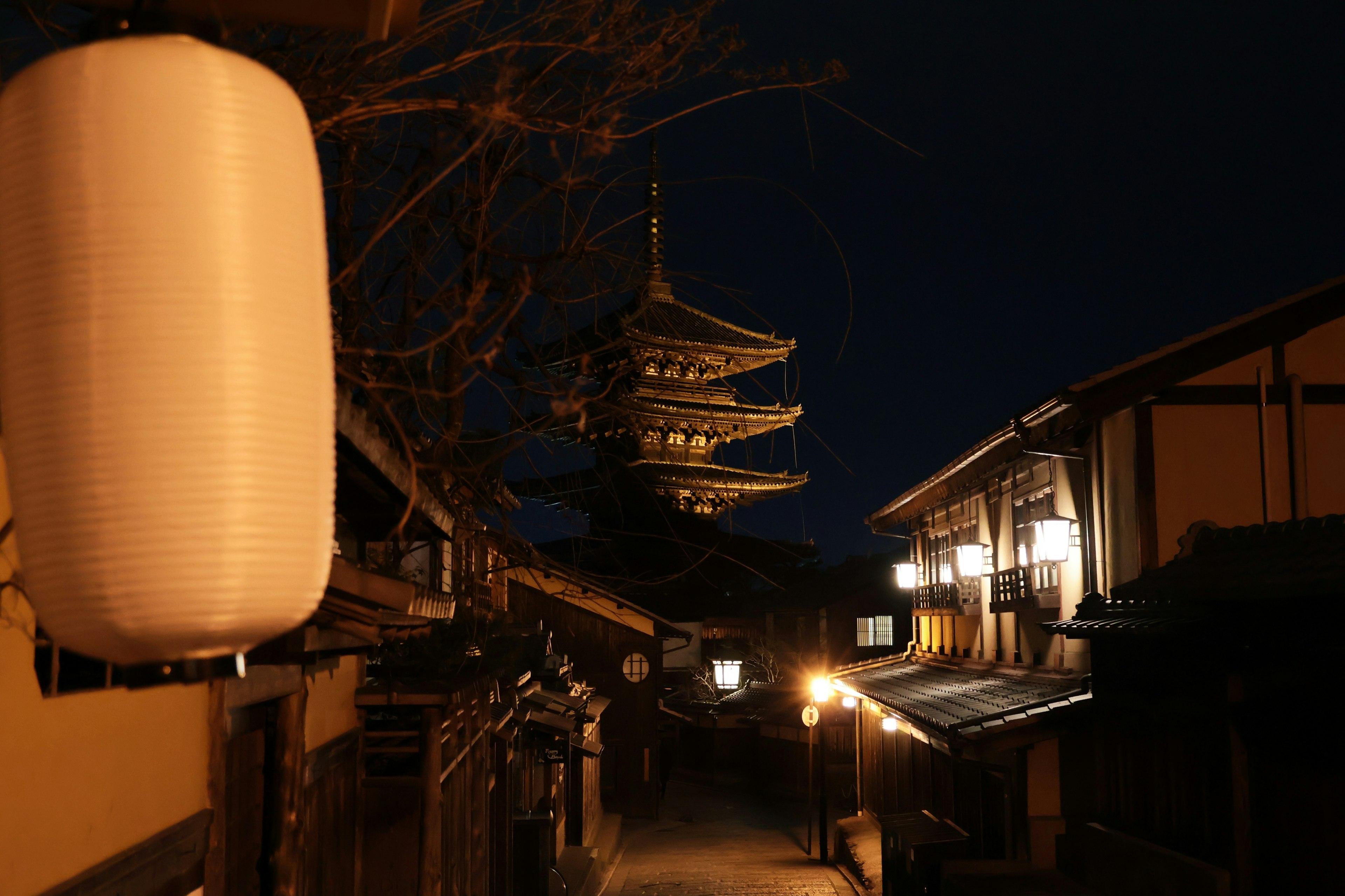 Vista notturna di una pagoda e una lanterna in una strada tradizionale