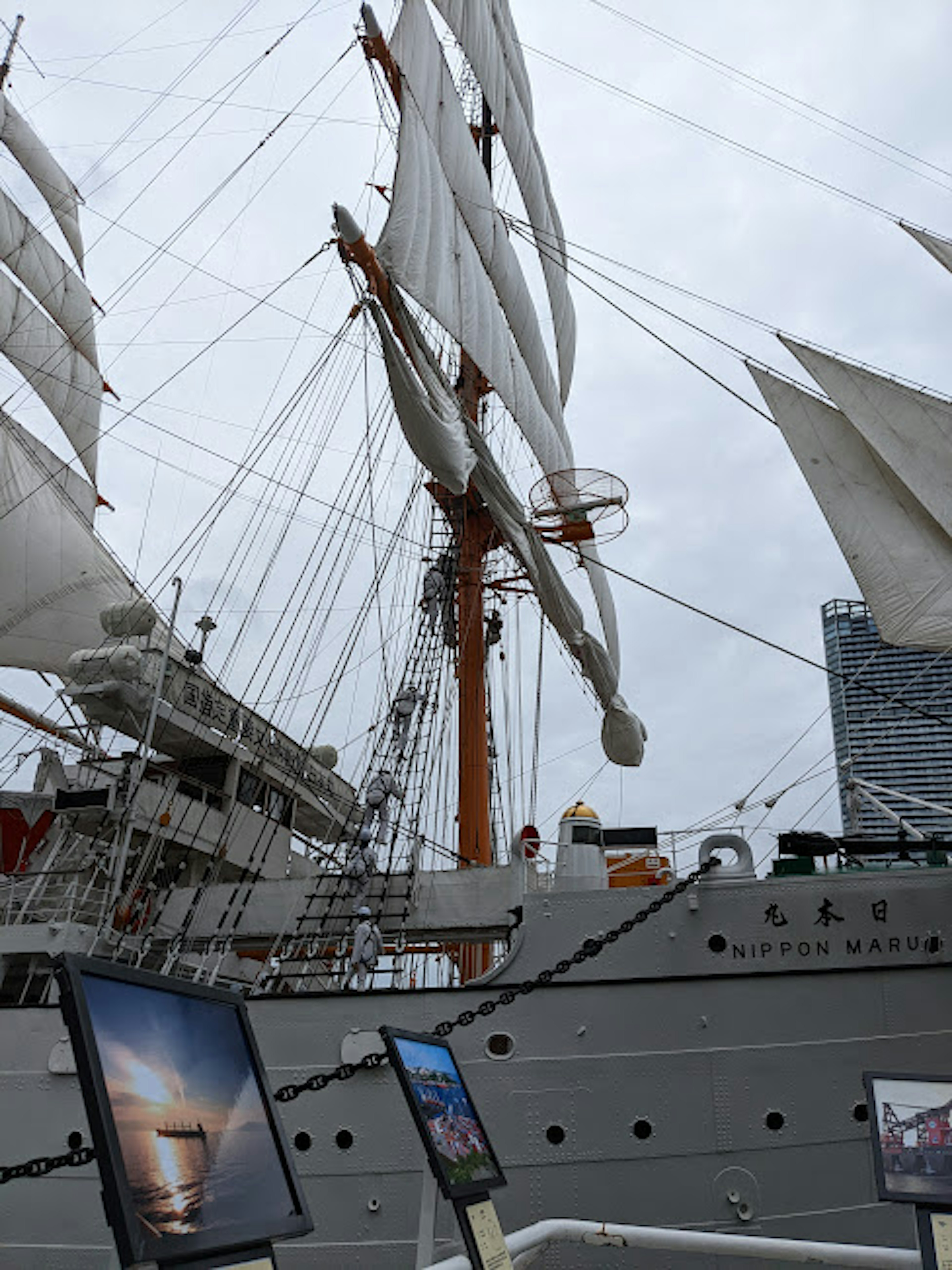 Gran barco de vela en exhibición con velas blancas y un mástil naranja