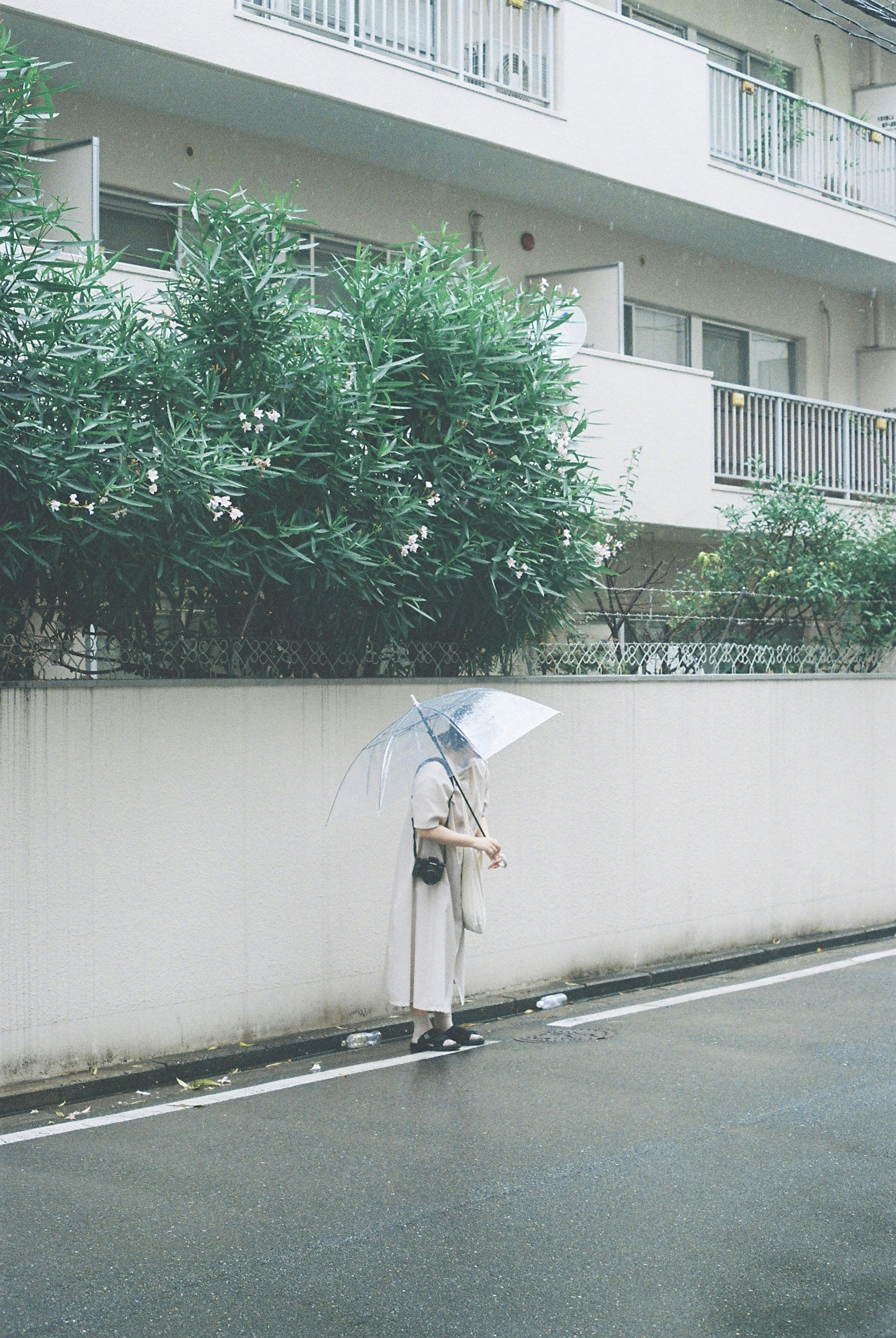 Une femme debout sous la pluie tenant un parapluie près d'un immeuble résidentiel