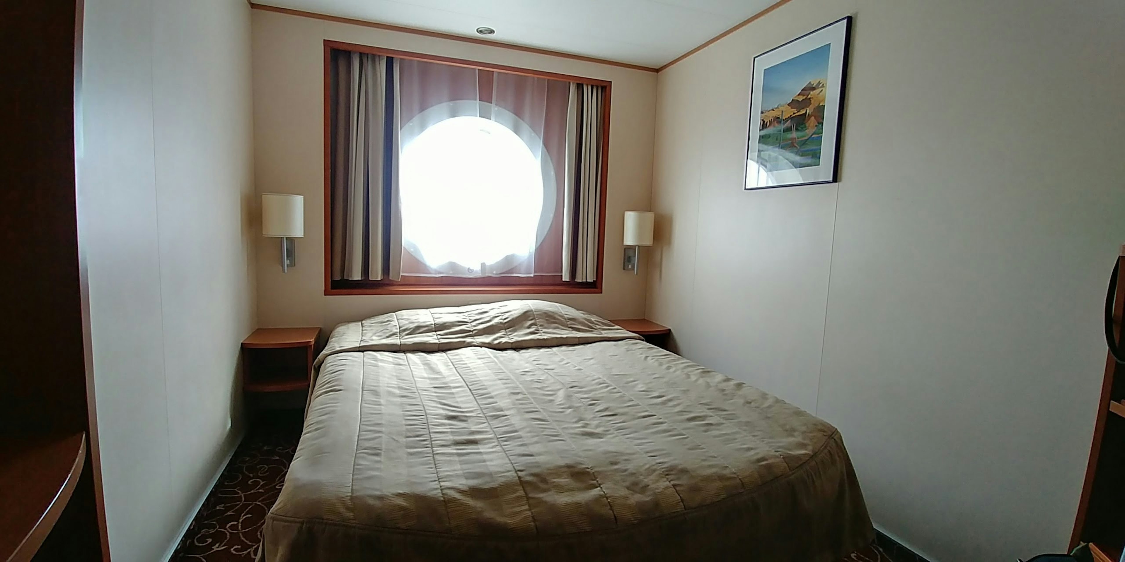 Dormitorio acogedor con cama y ventana redonda con cortinas en tonos cálidos