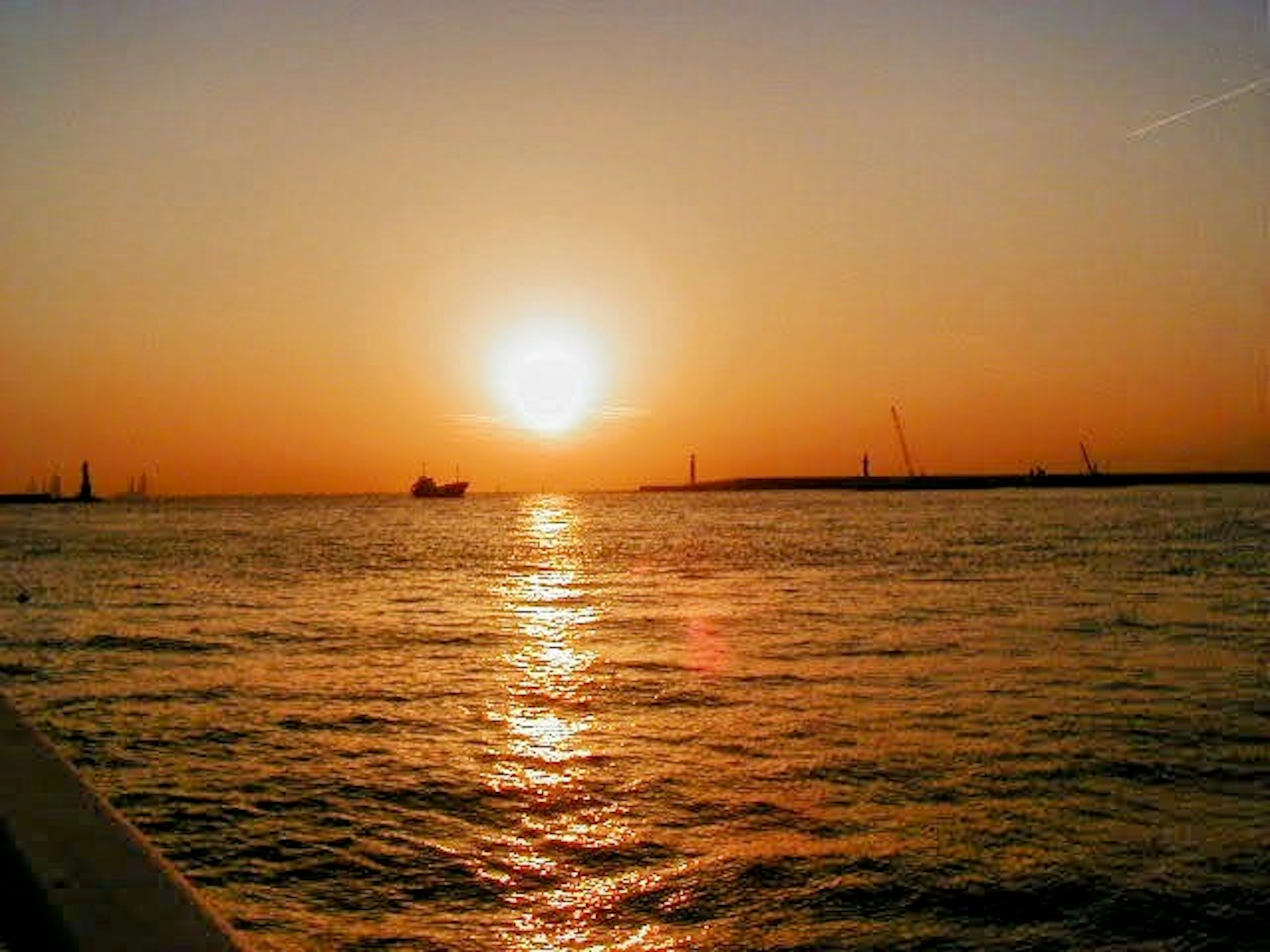 夕日が海に沈む美しい風景 船と灯台が遠くに見える