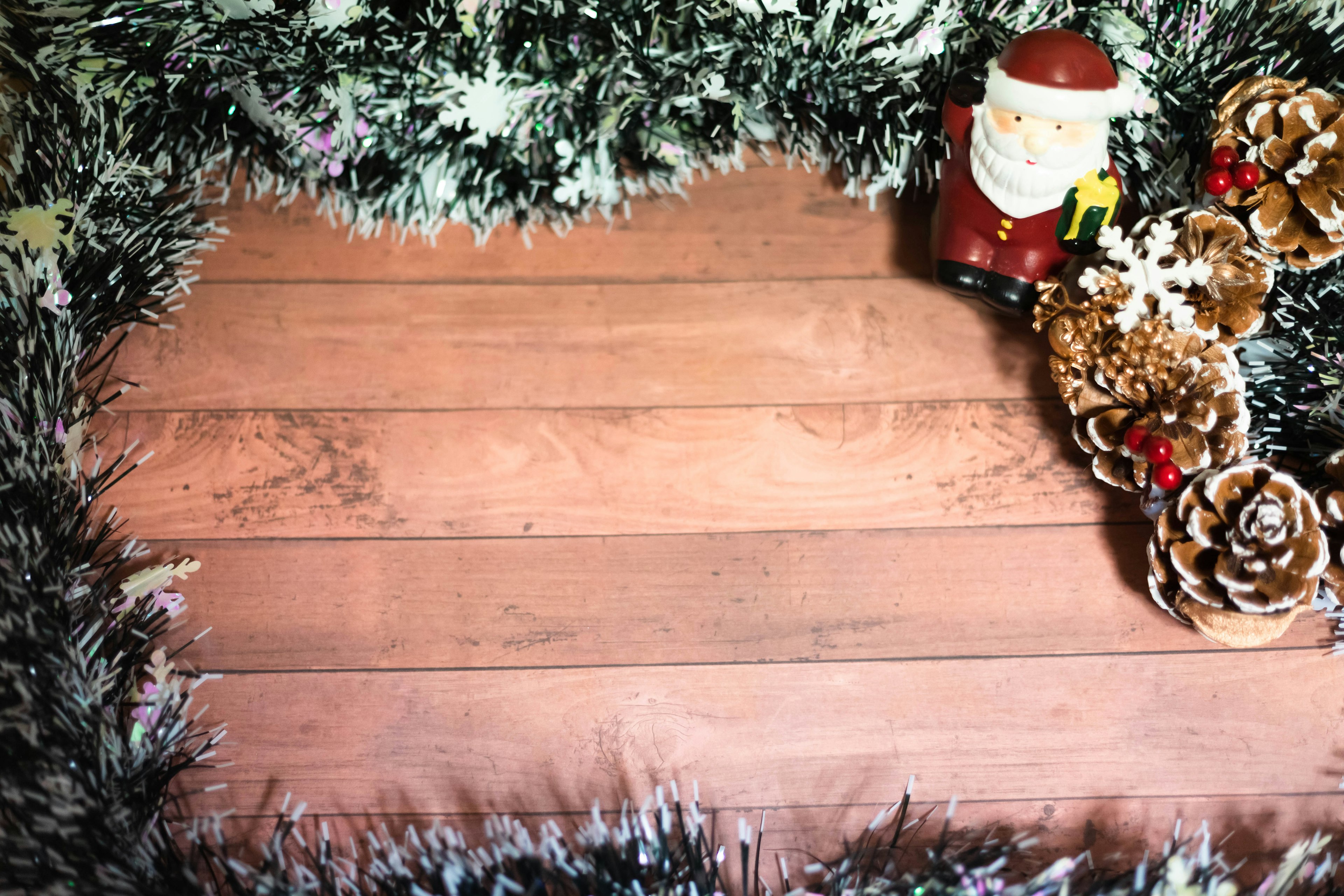 Decoración navideña con una figura de Santa y piñas sobre una mesa de madera