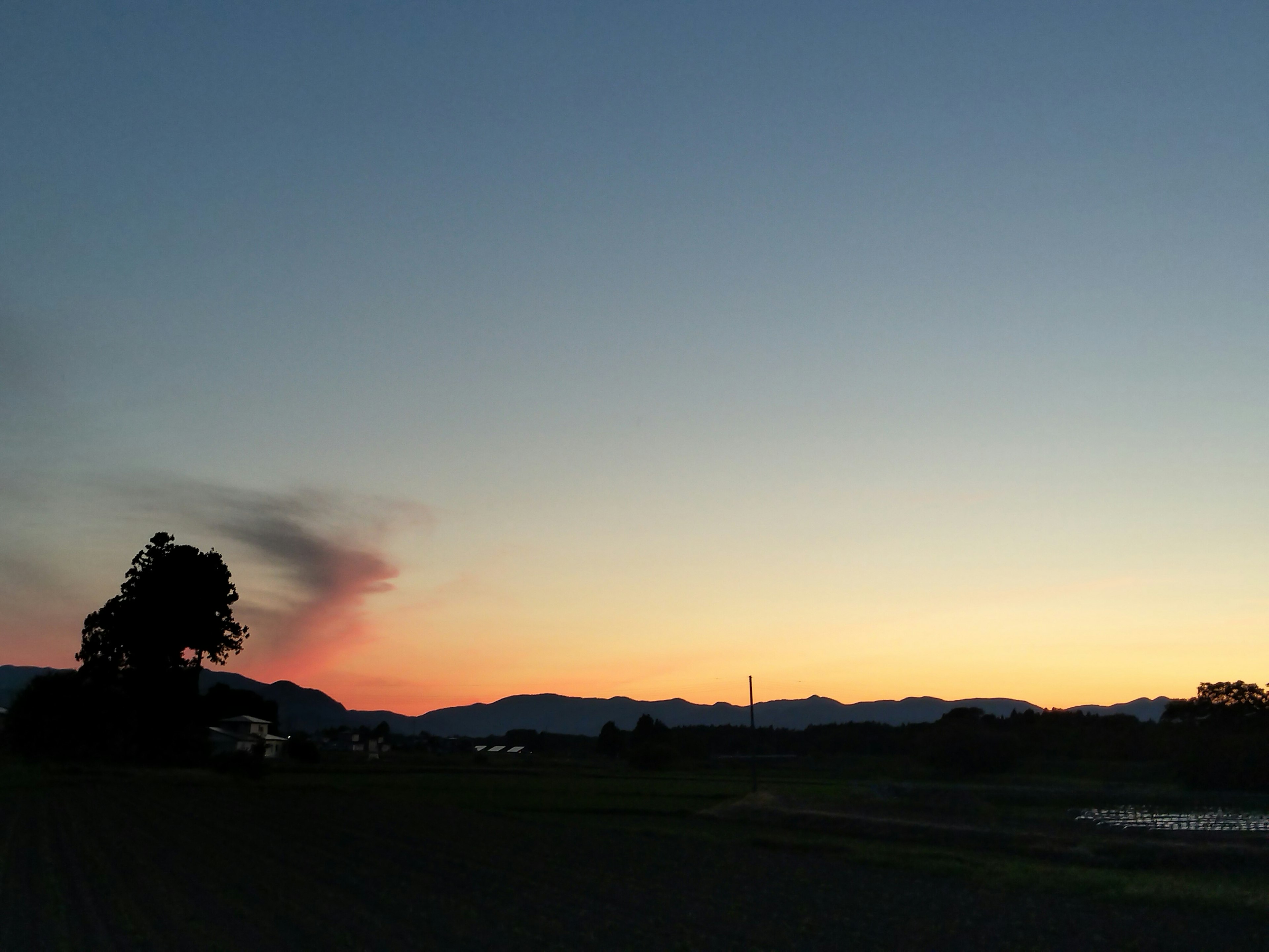 夕暮れの空に山々と煙のような雲が見える風景