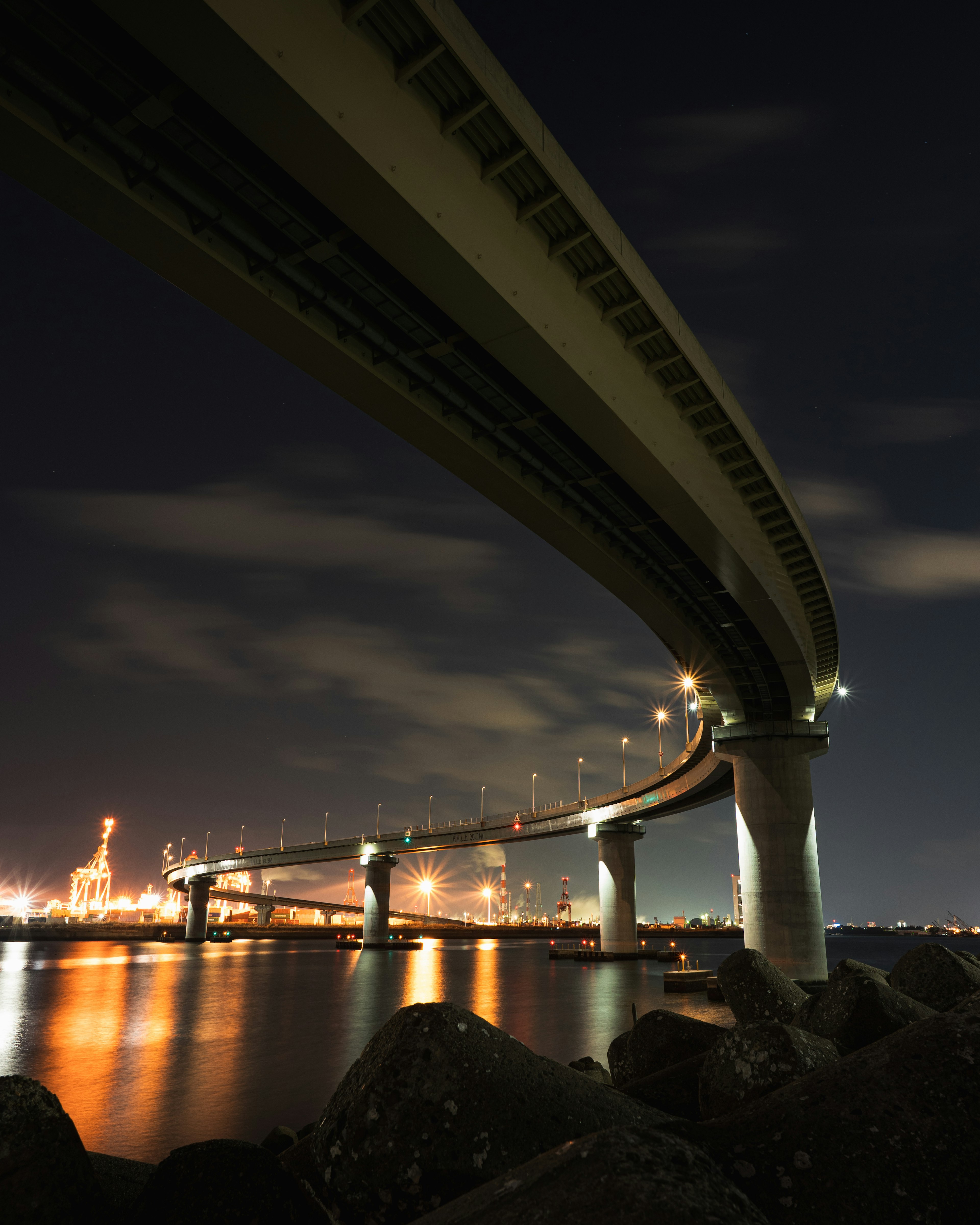 View of a bridge from below at night reflecting on the water with beautiful lighting