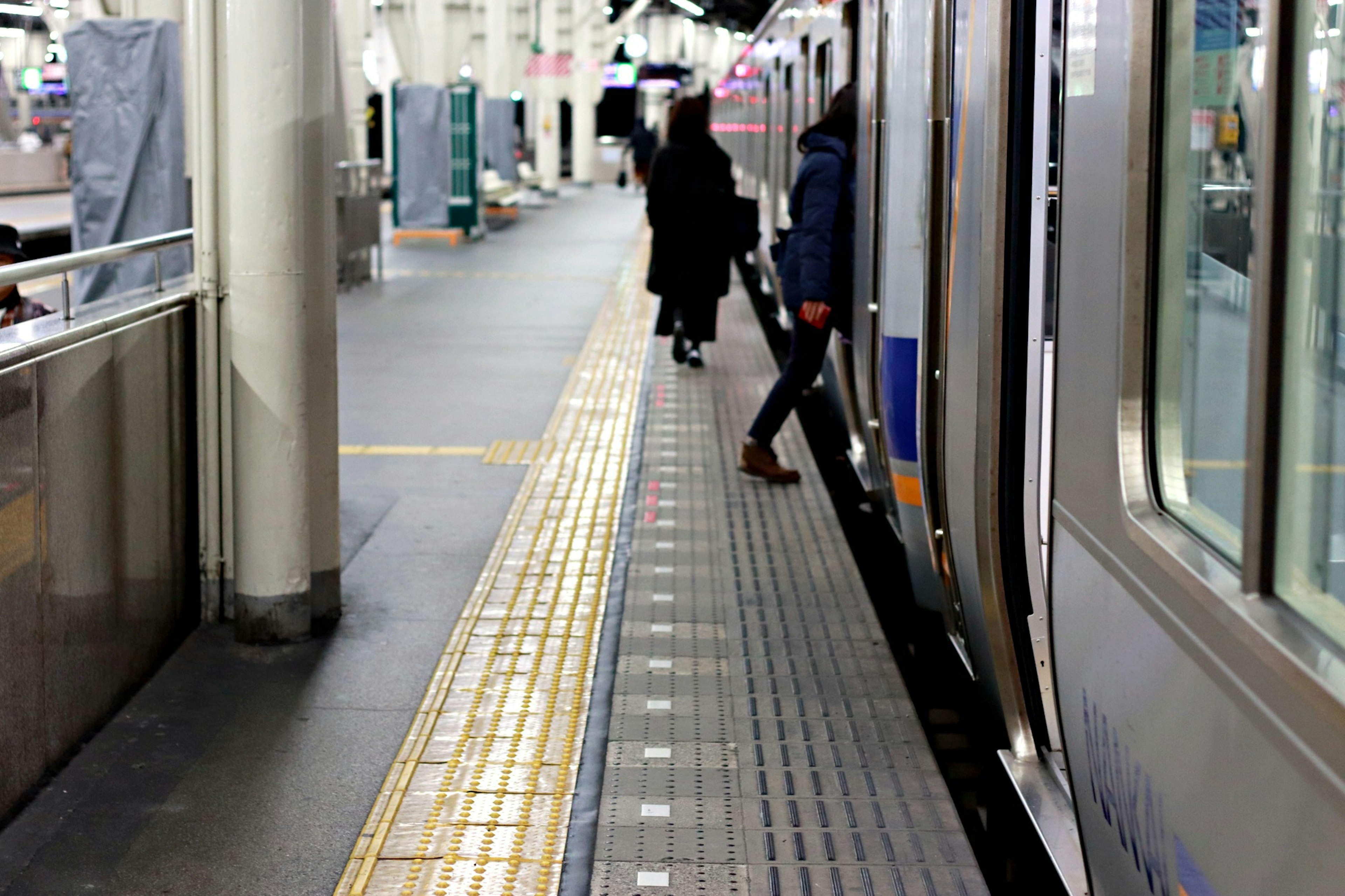 Orang-orang berdiri di platform kereta di samping kereta