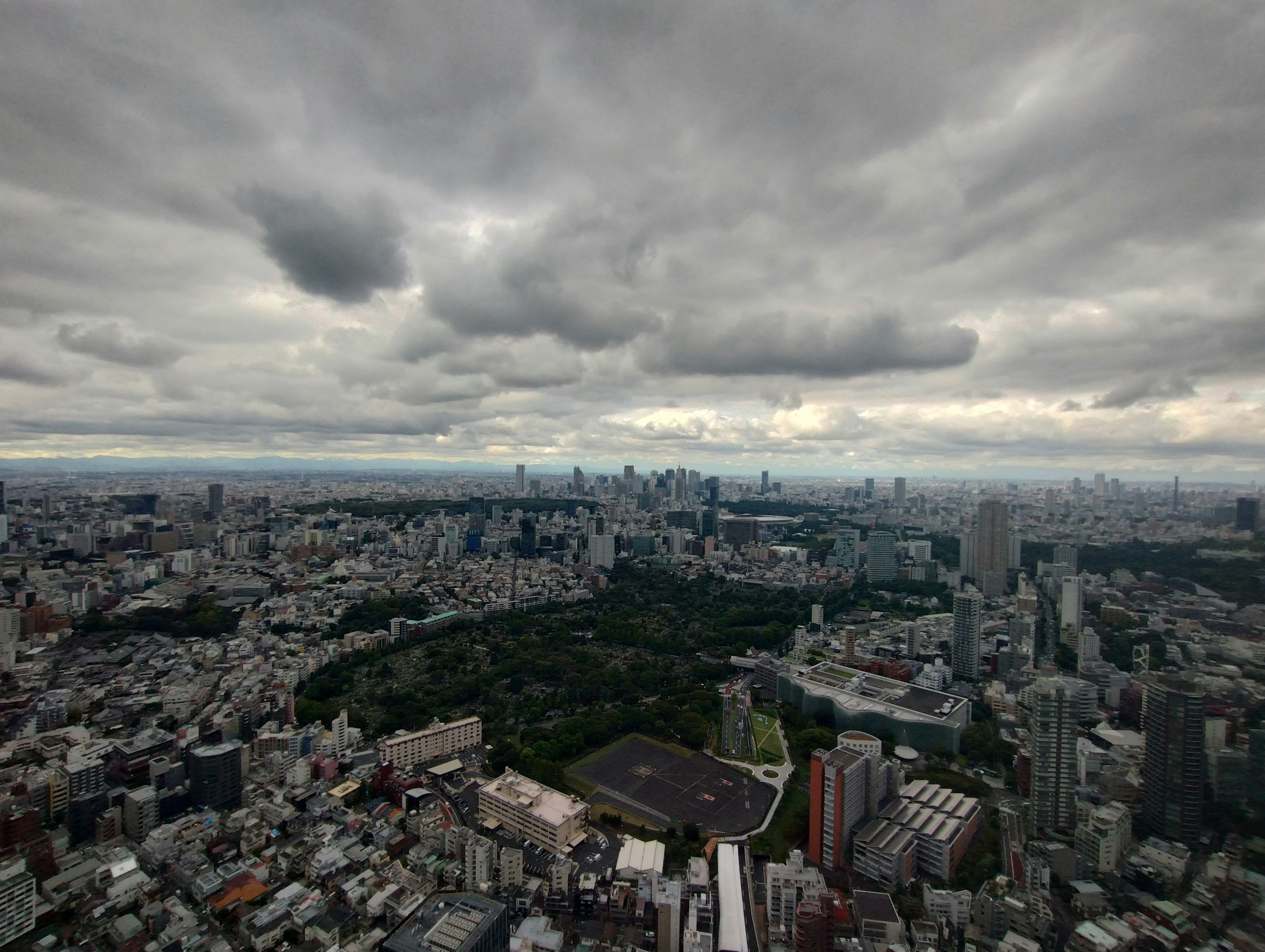 Vista aérea de Tokio que muestra el paisaje urbano y el parque bajo un cielo nublado