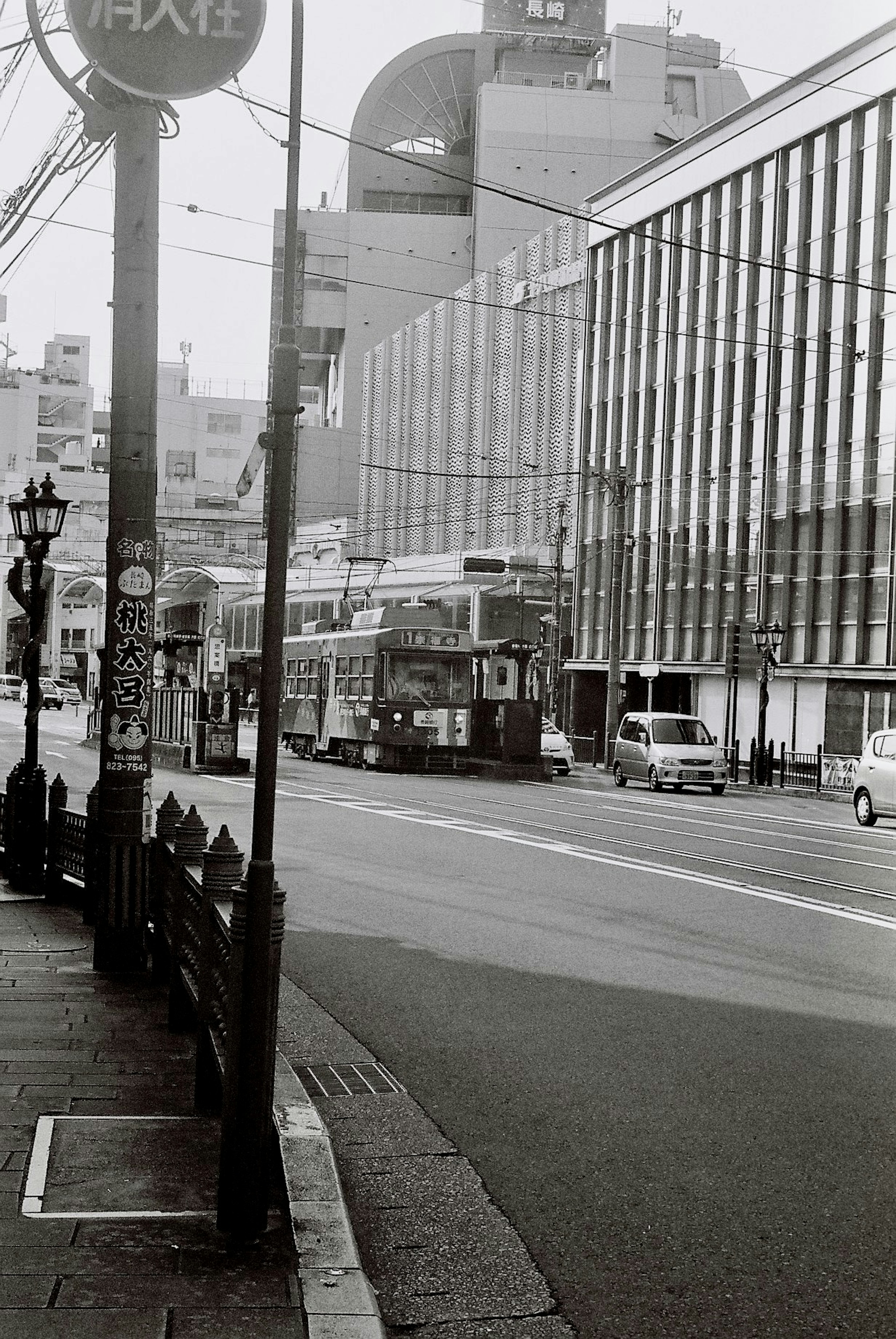 Black and white street scene featuring a tram and buildings