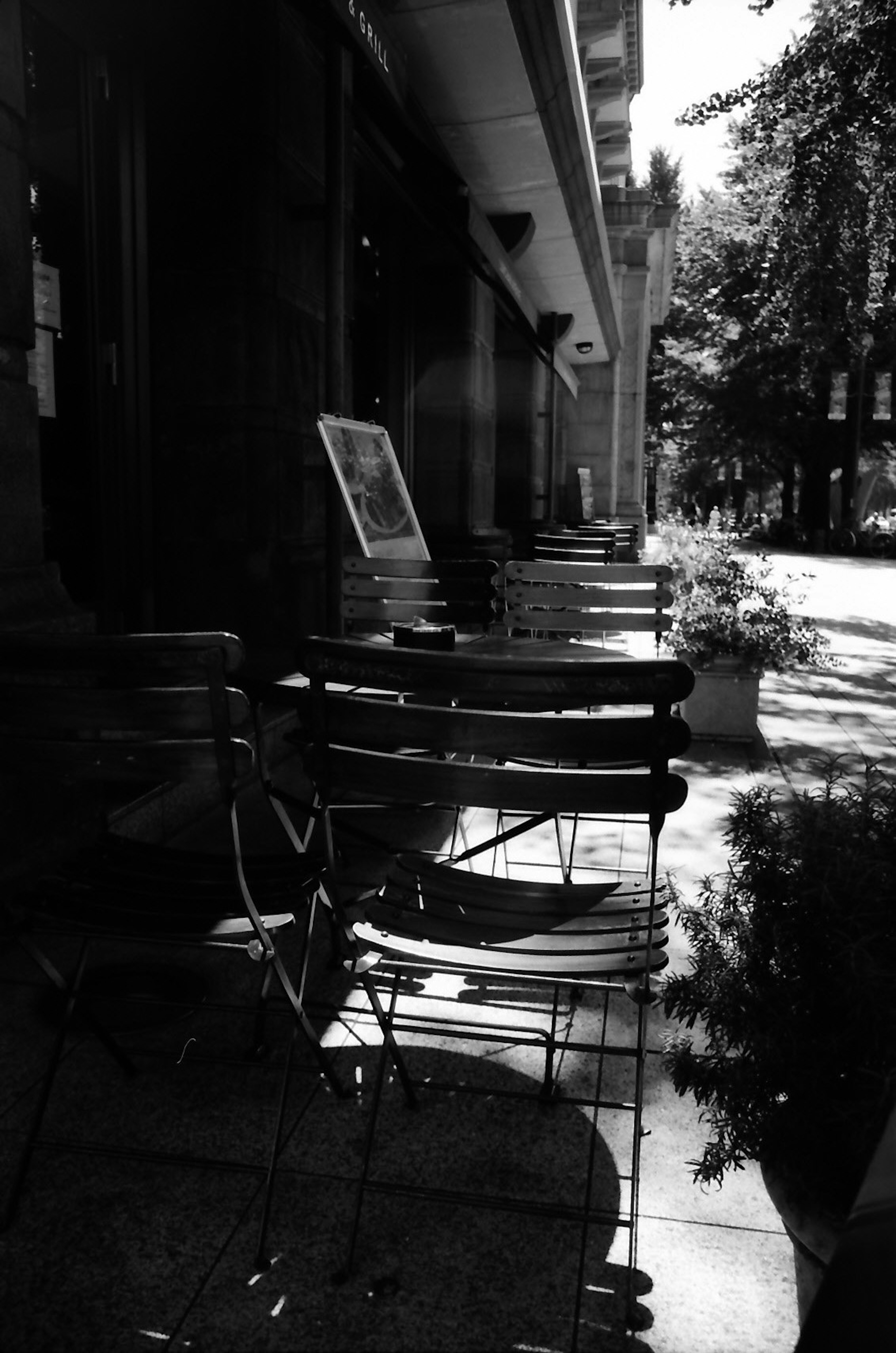 Scena in bianco e nero di sedie e tavoli allineati su una terrazza di caffè