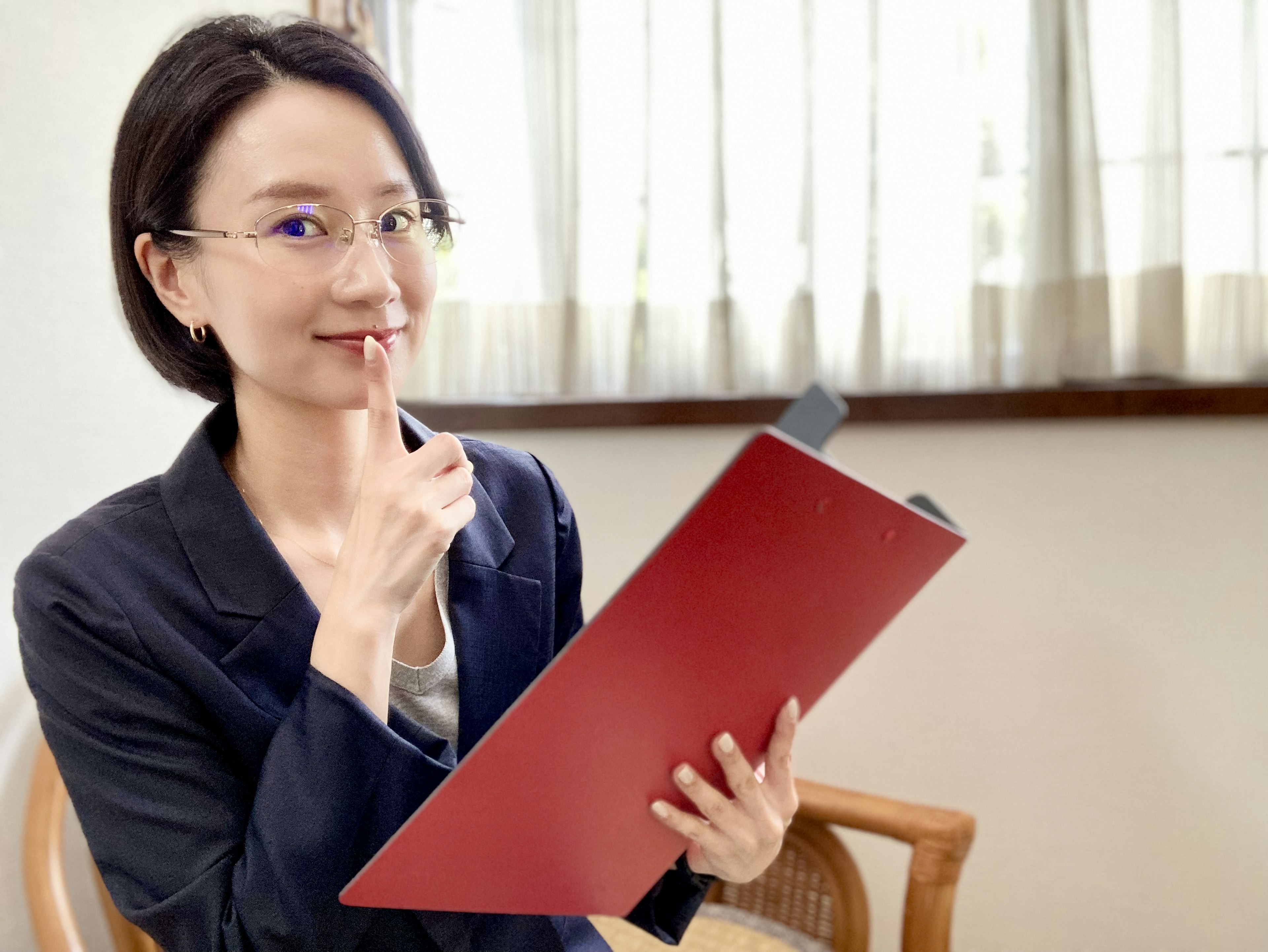 Woman holding a red folder with a thoughtful expression