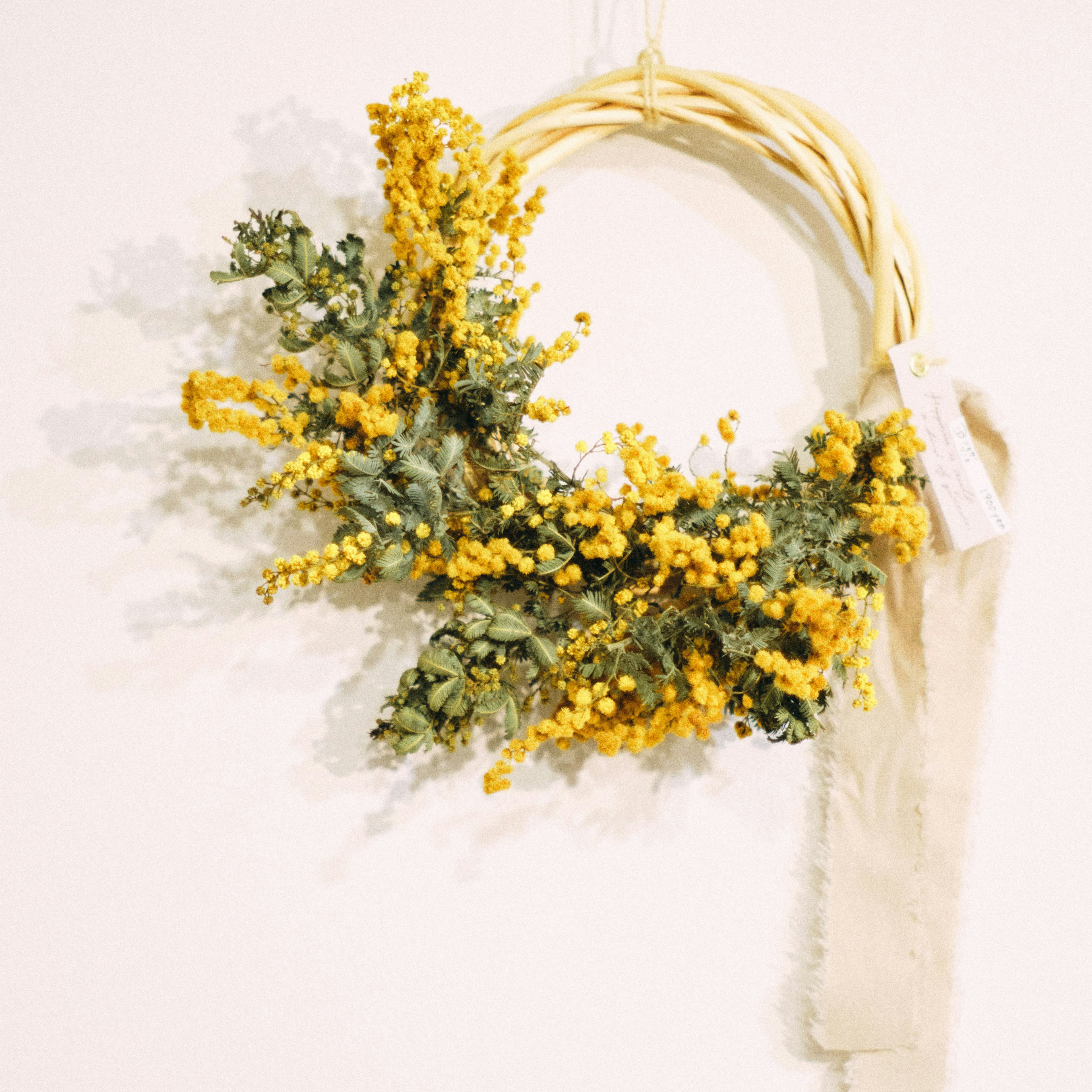 A decorative wreath made of yellow flowers and green leaves hanging on a wall