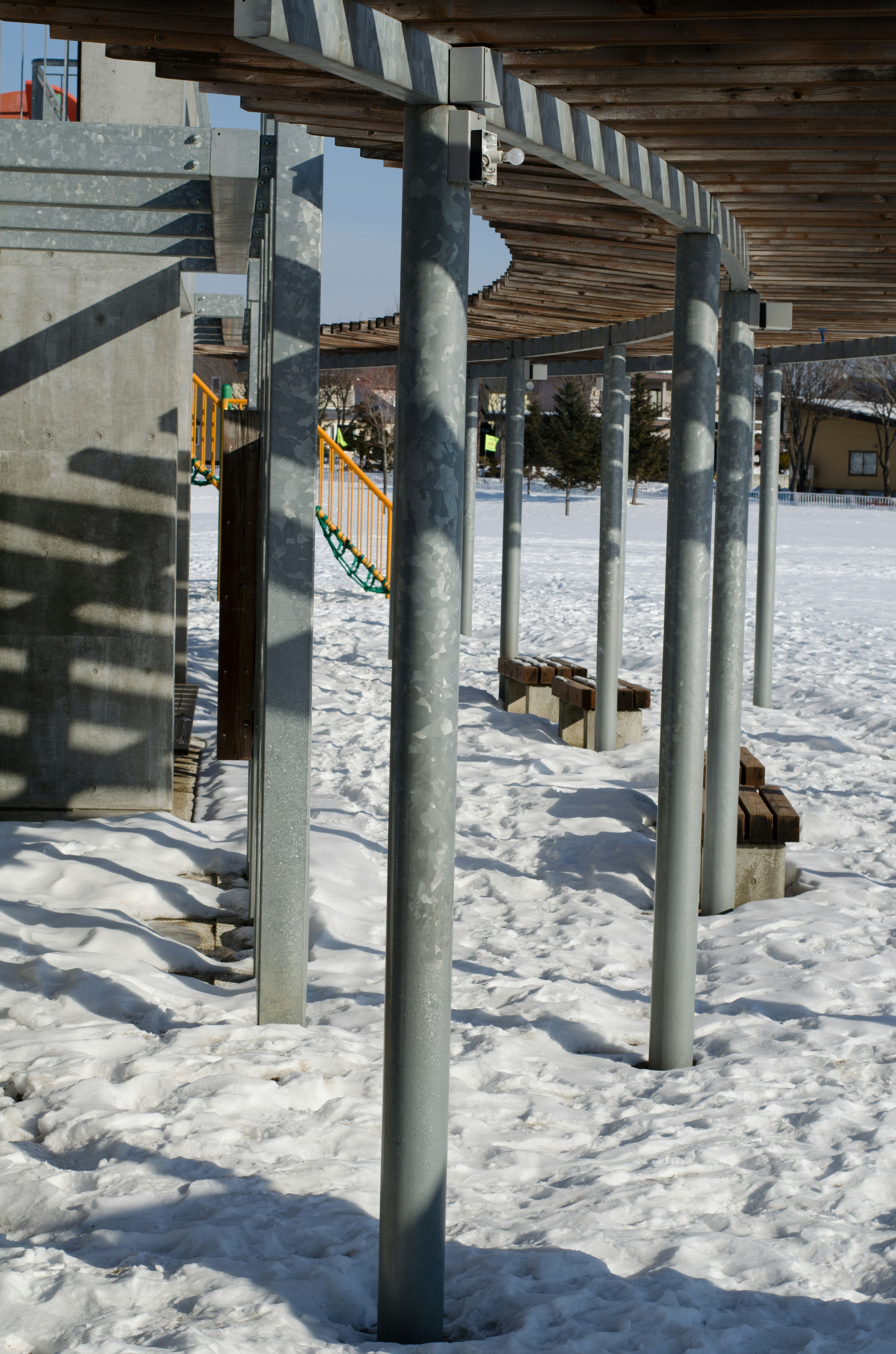 雪に覆われた地面に立つ金属製の柱と木の構造物