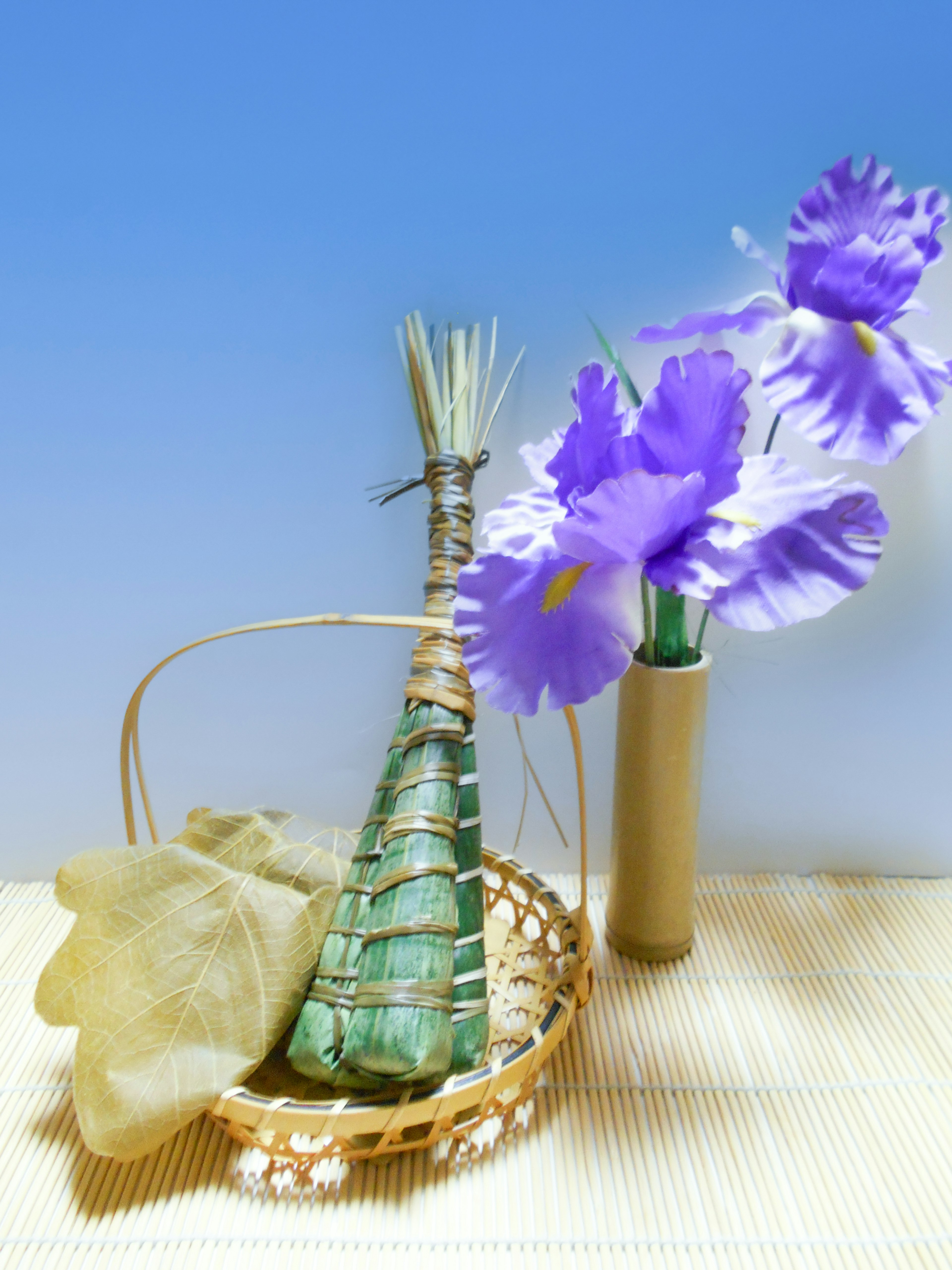 Beautiful arrangement featuring purple flowers in a bamboo vase and a bundle of leaves