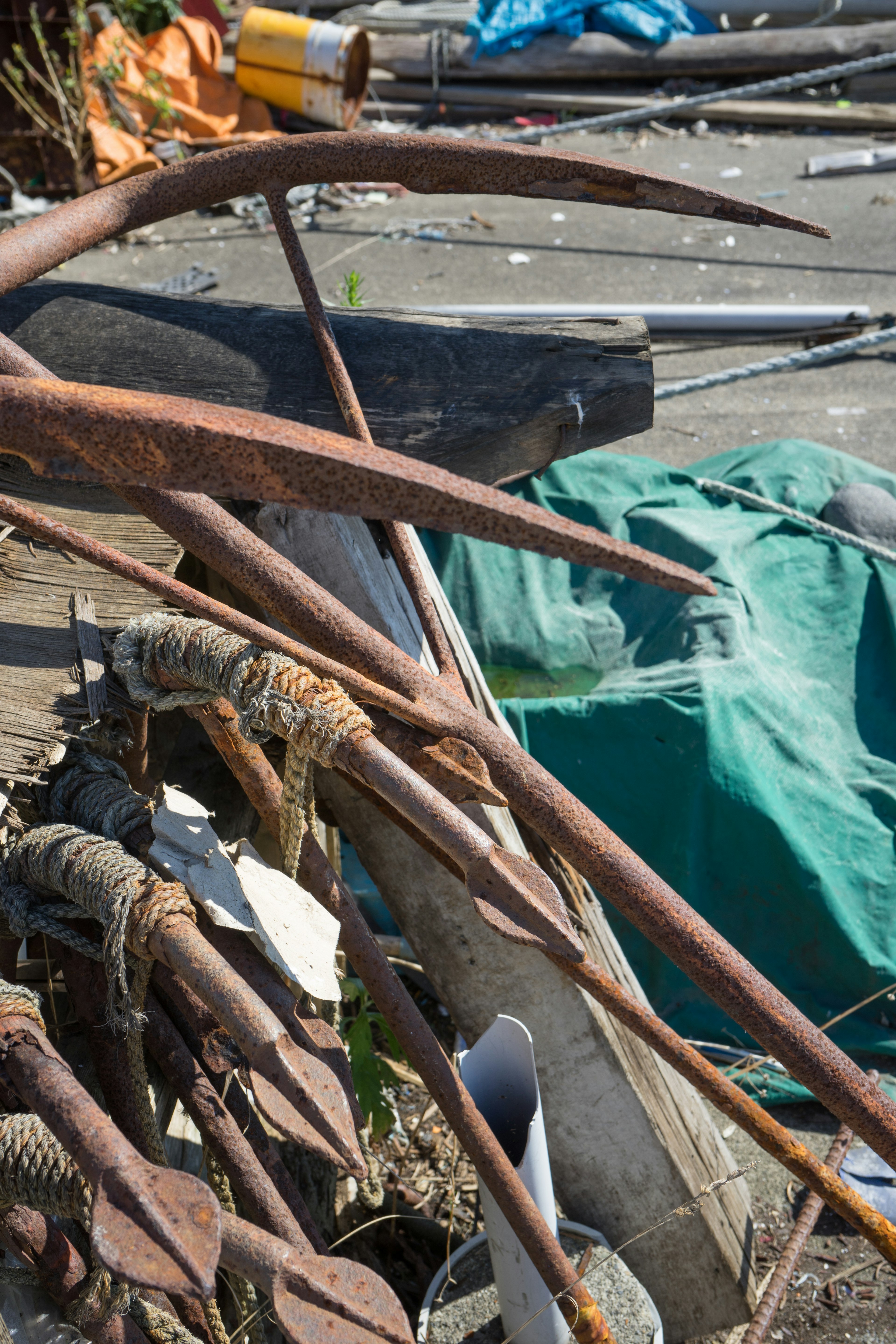 A collection of rusty metal tools and a green tarp among debris