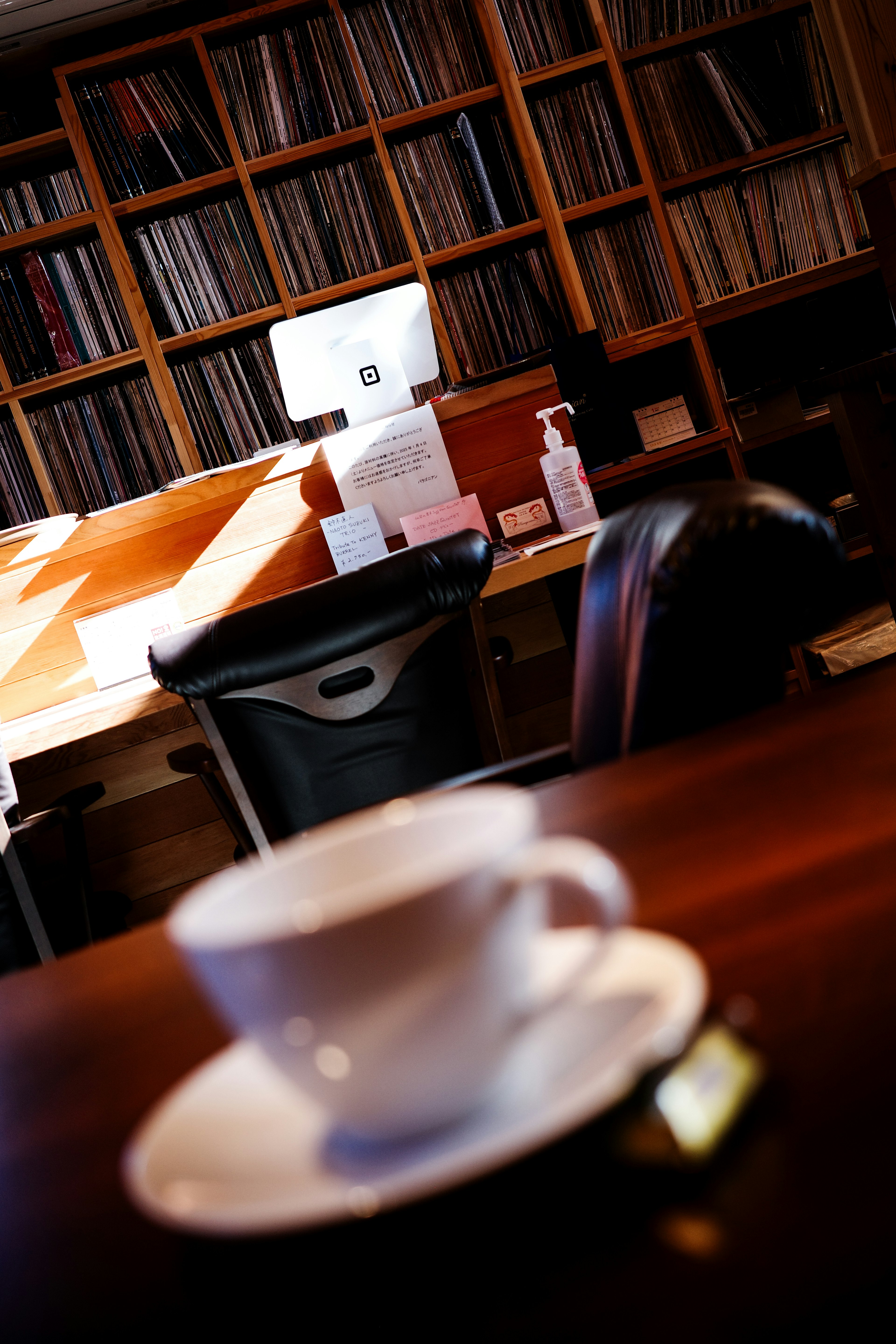White coffee cup on a wooden table with a bookshelf in the background