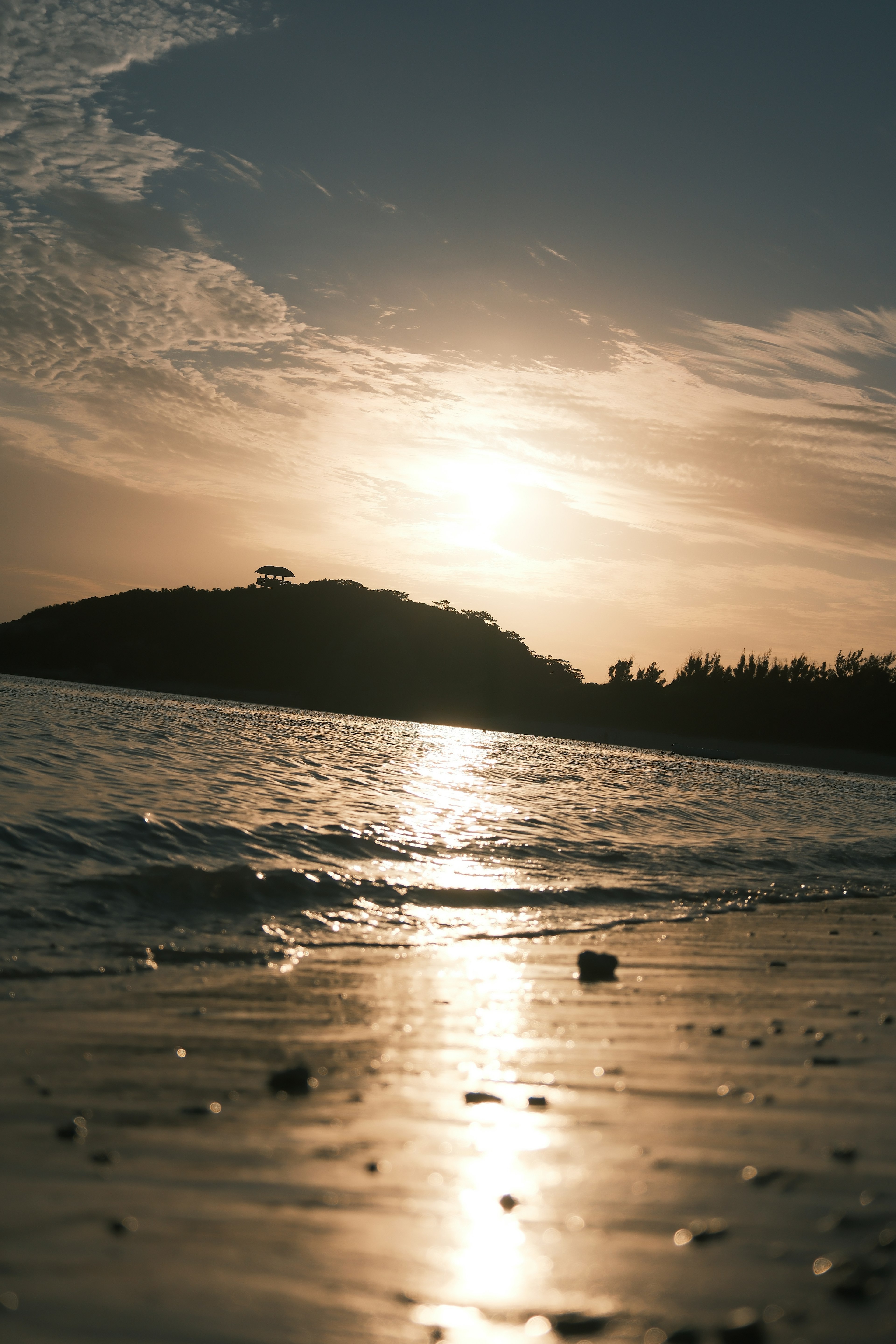 Sunset over the ocean with gentle waves and sandy beach