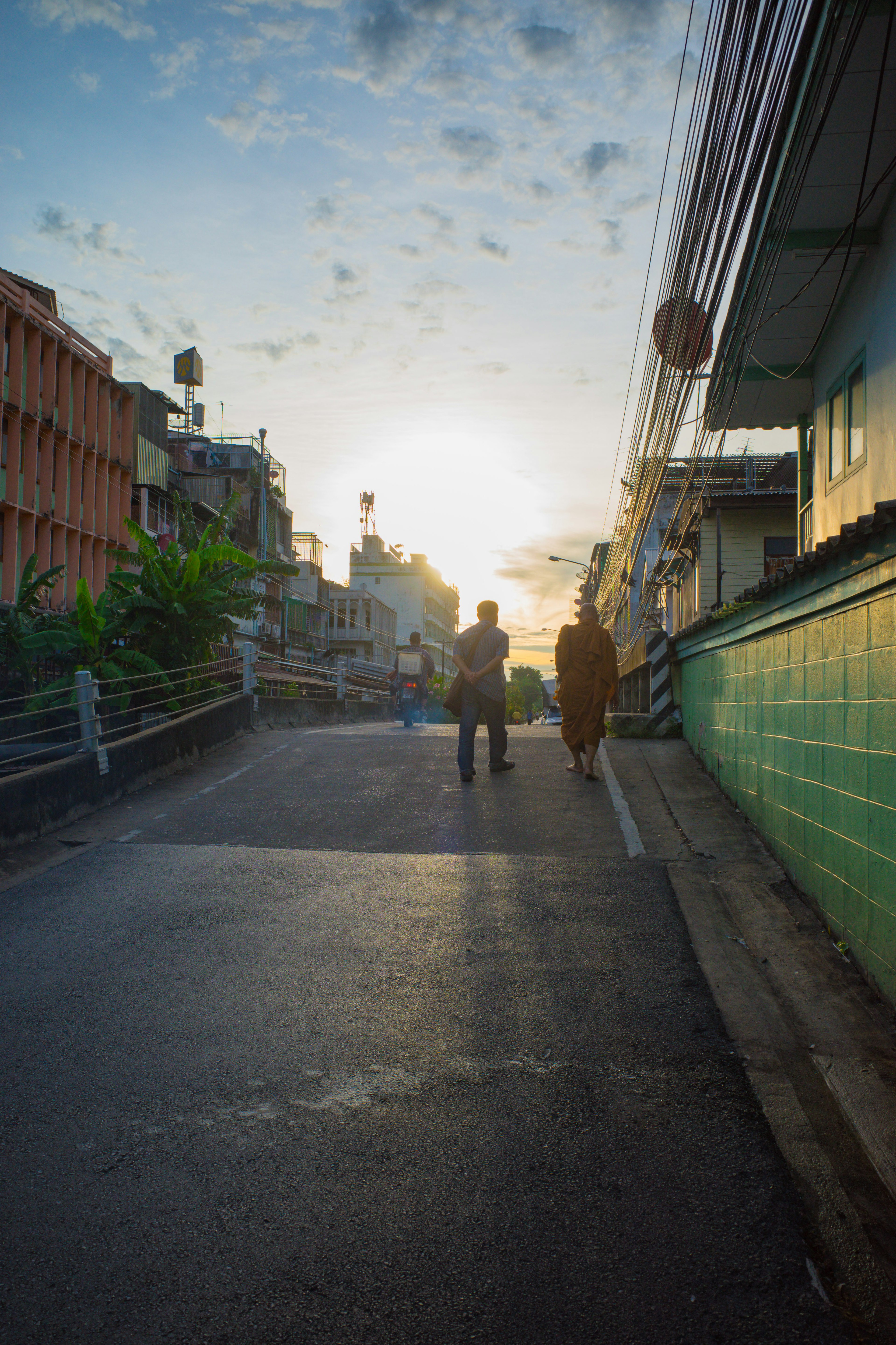 Silhouettes de deux personnes marchant dans une rue au coucher du soleil