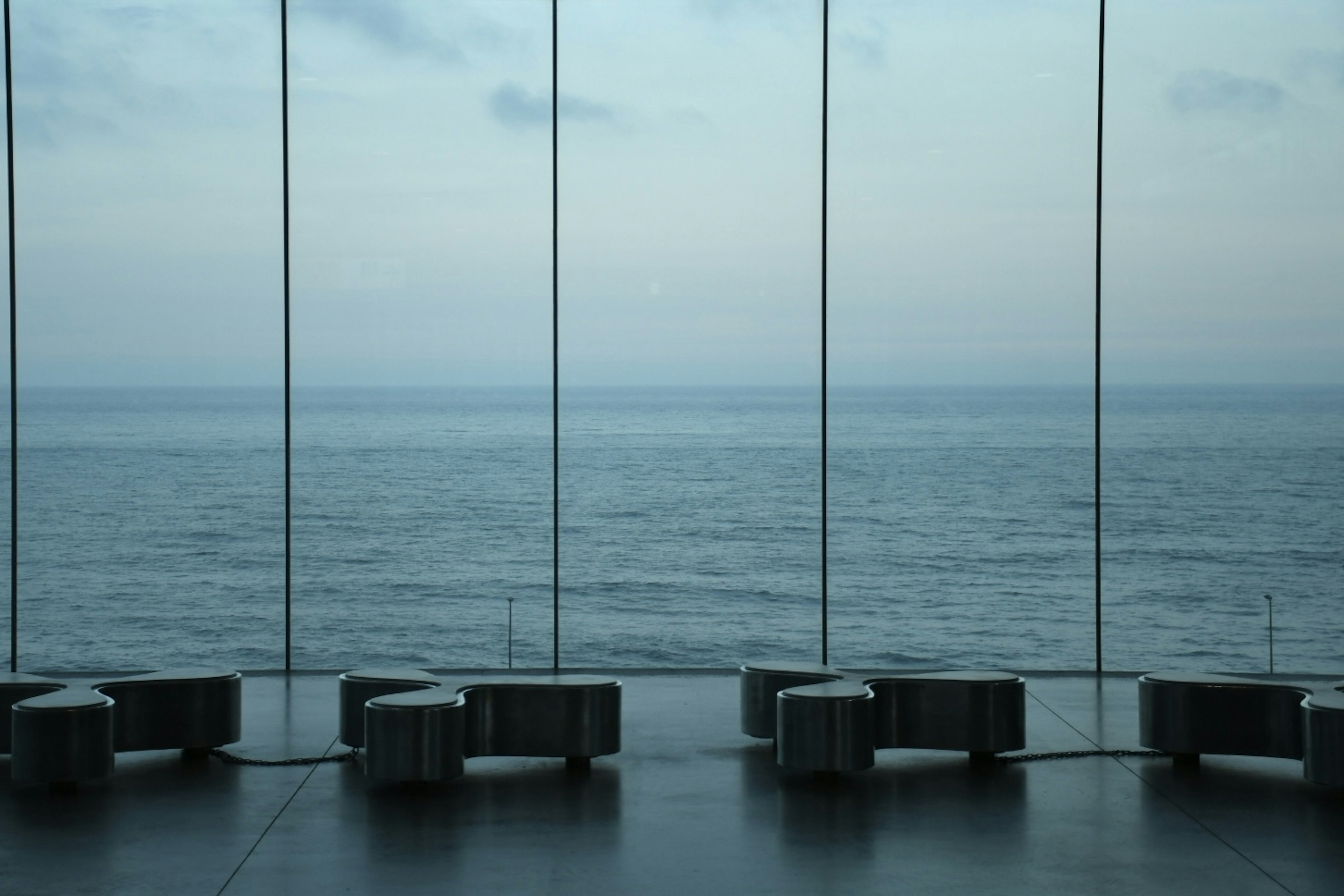 Interior space with glass walls overlooking the sea and arranged seating