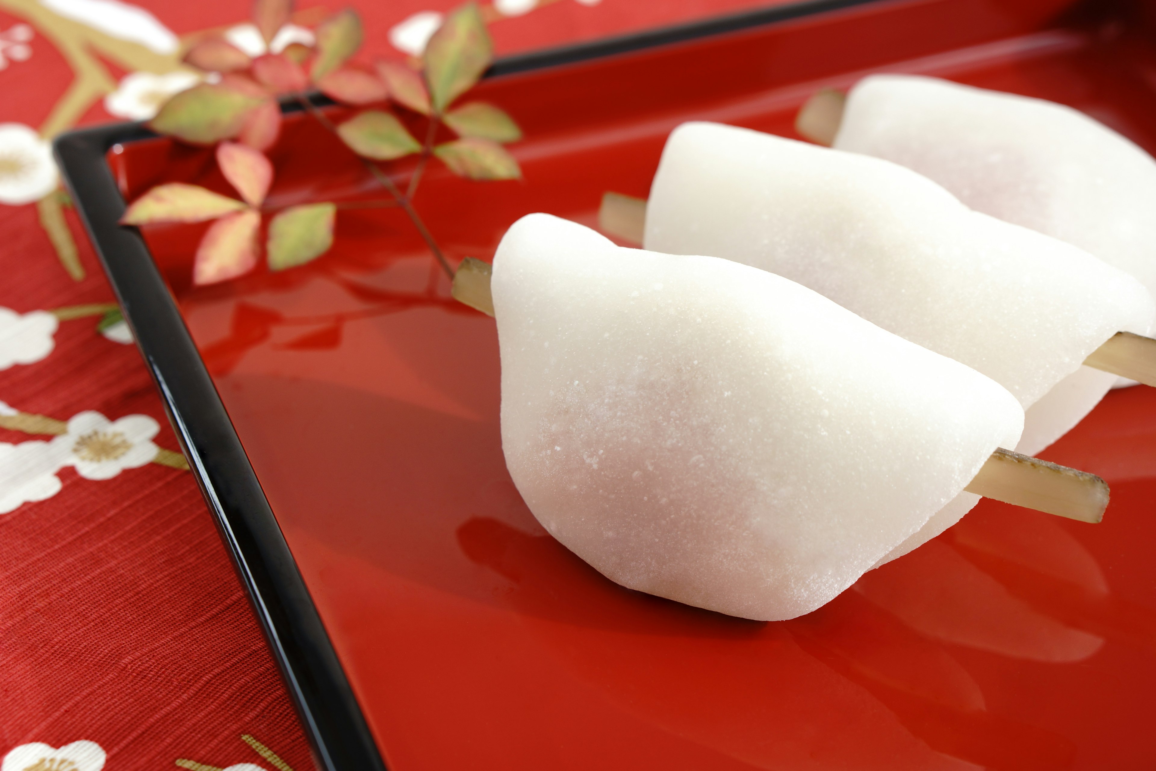 Three white Japanese sweets on a red plate