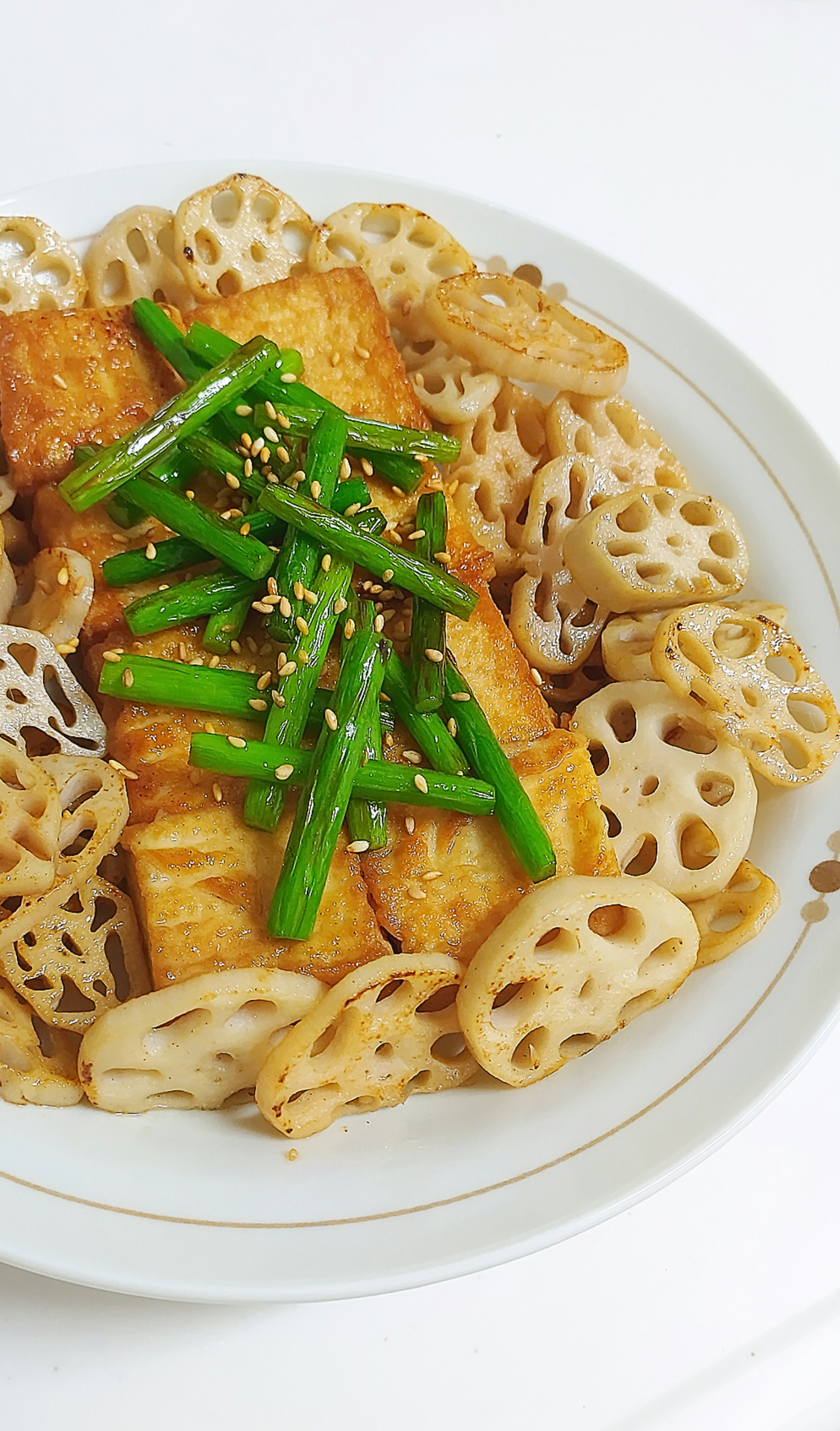 Piatto di tofu fritto con radici di loto guarnito con cipollotti