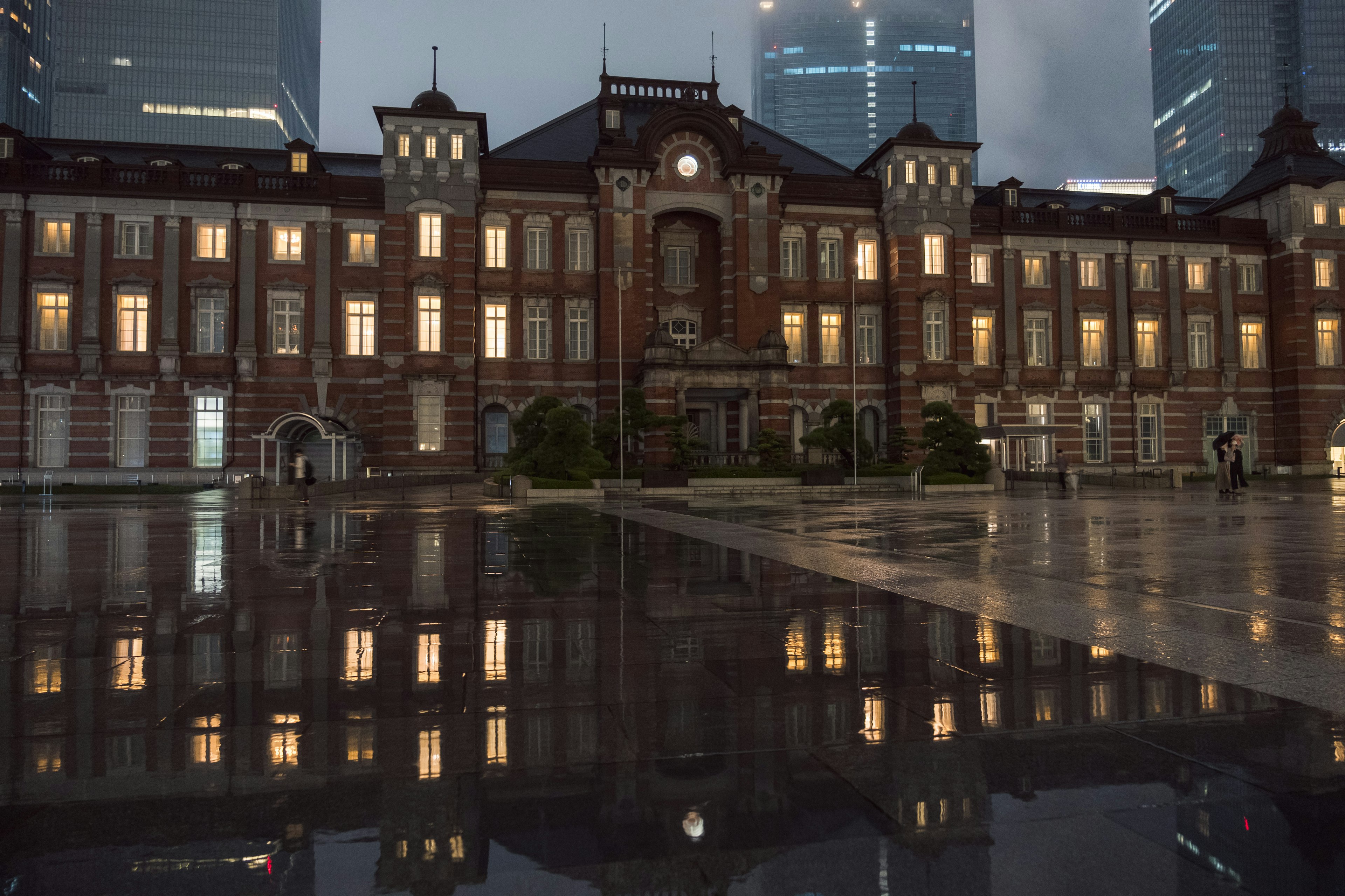 Bangunan bersejarah Stasiun Tokyo yang terpantul di permukaan basah dengan lampu kota