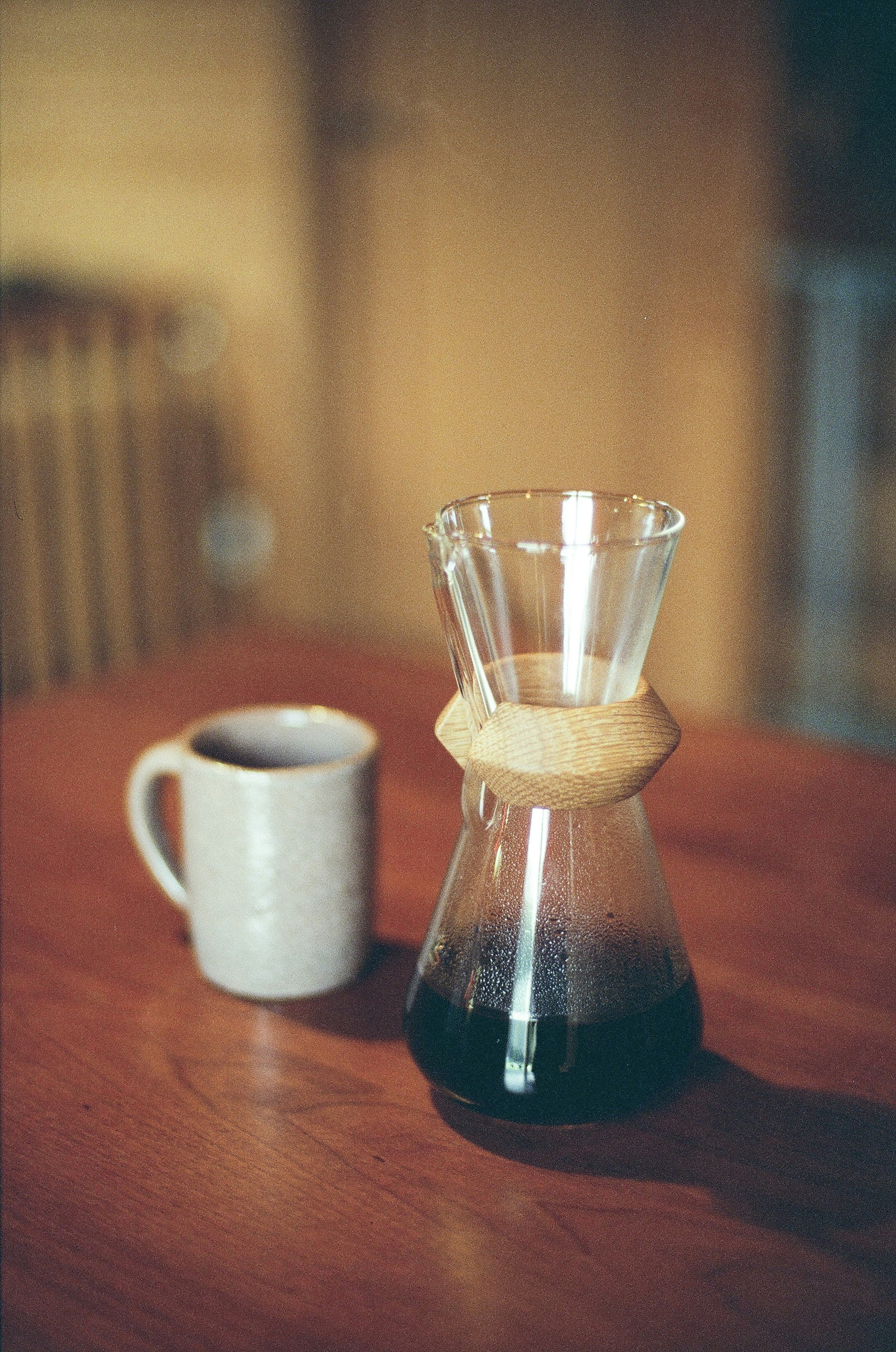 A coffee maker and a cup of coffee placed on a wooden table