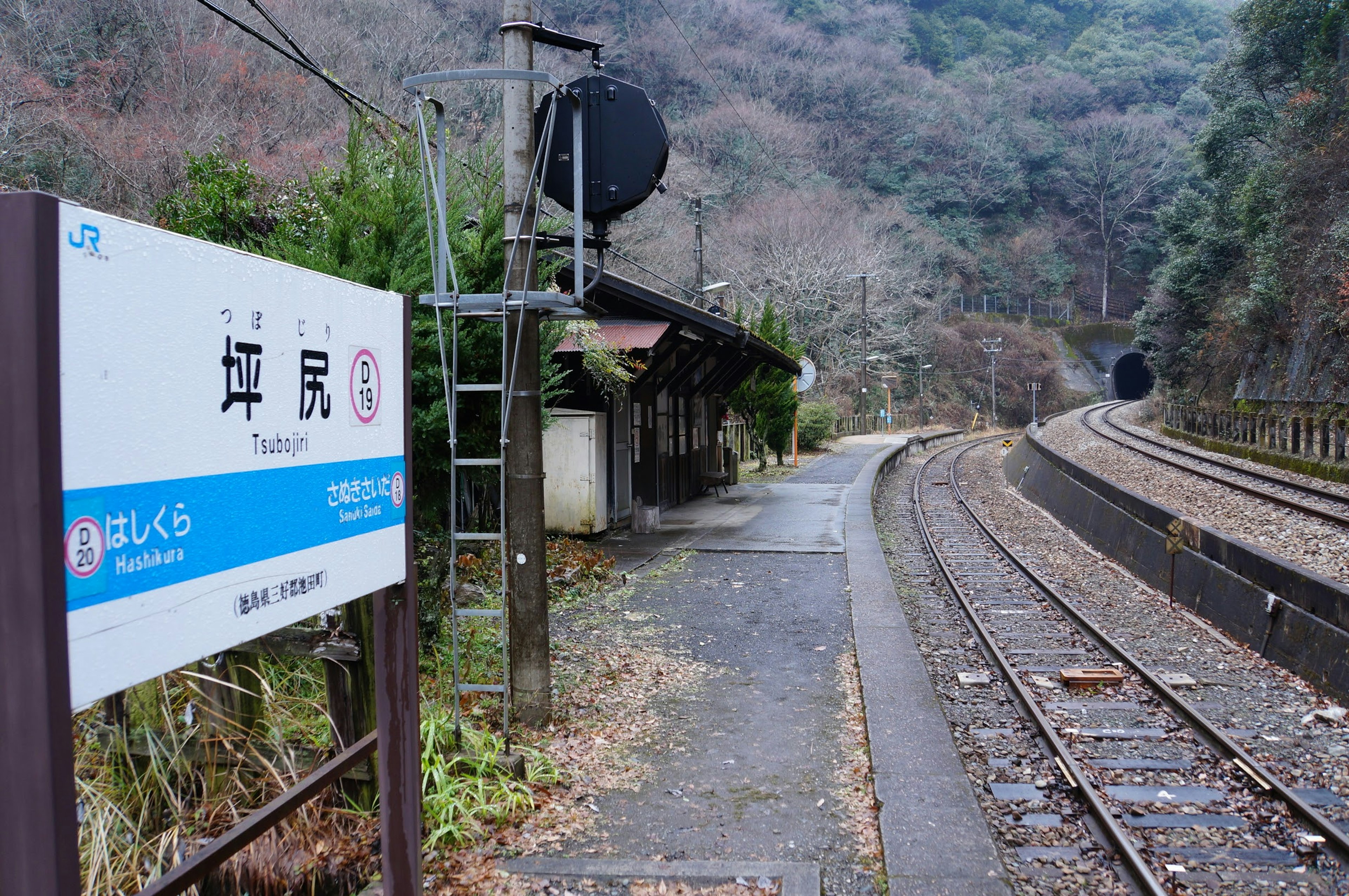 Quiet mountain station view featuring a station sign and visible tracks