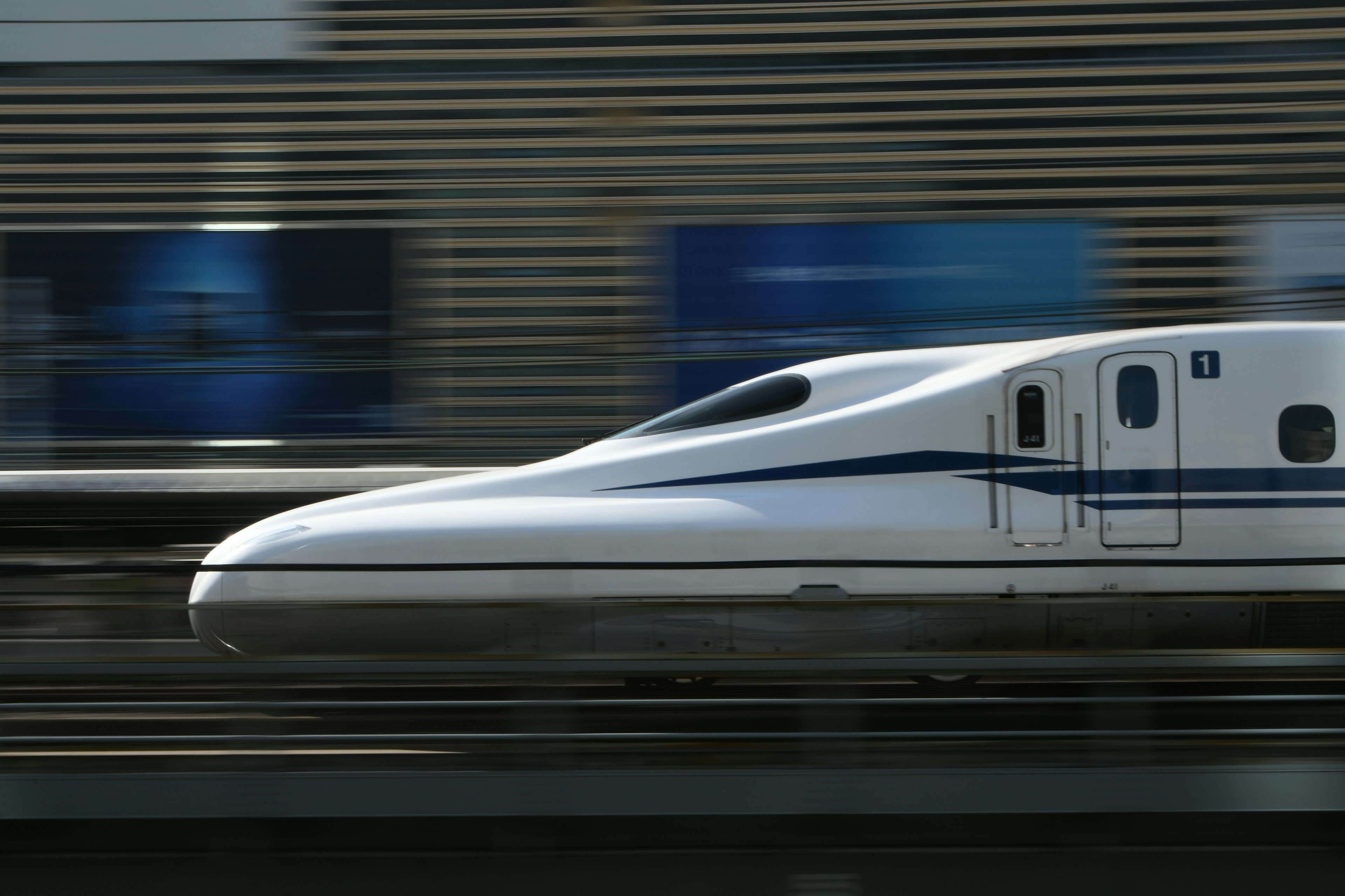 Treno Shinkansen che sfreccia oltre una stazione