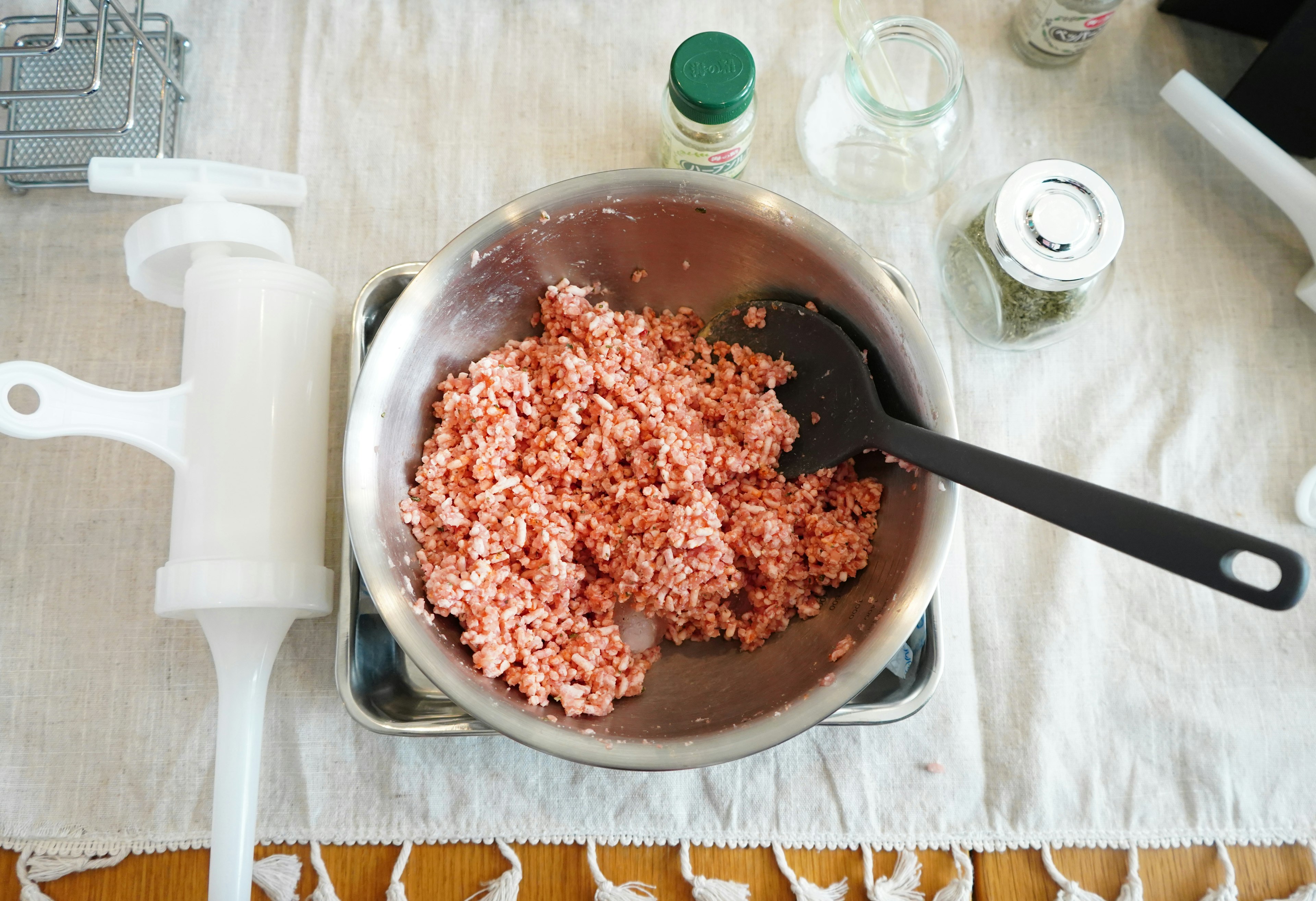 A bowl of minced meat with a spatula and kitchen tools on a table