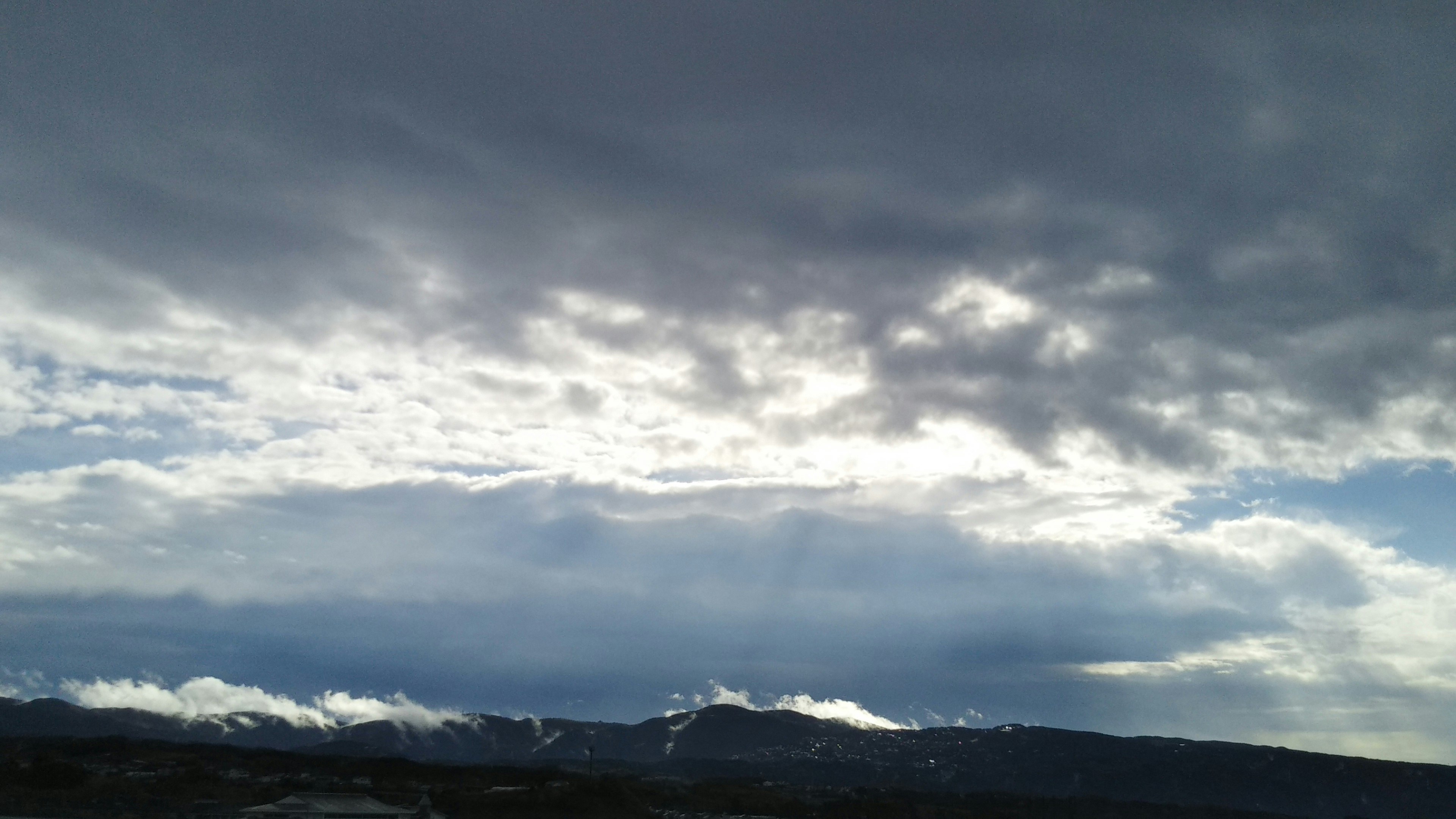 Paysage montagneux dramatique avec contraste entre nuages sombres et ciel bleu