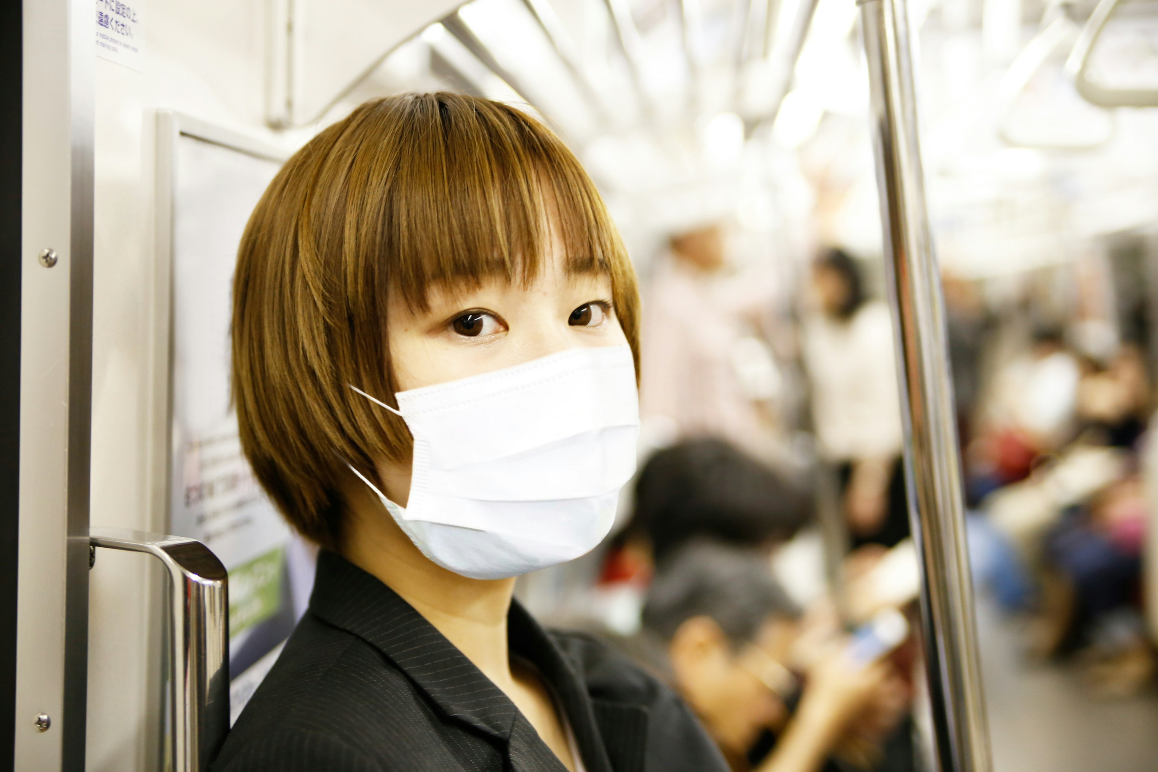 A woman with short hair wearing a mask in a subway car