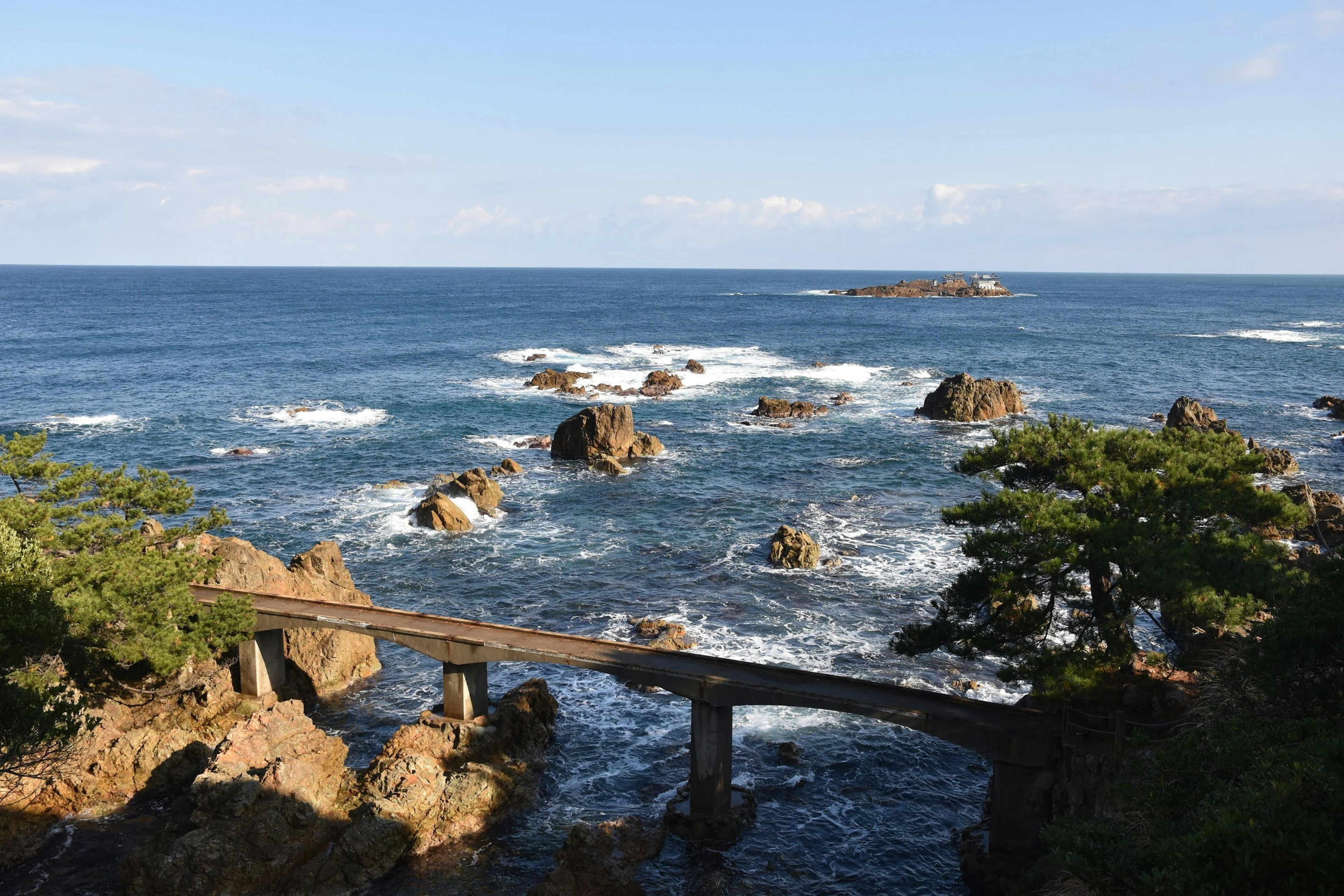 青い海と岩の景色にかかる木製の橋