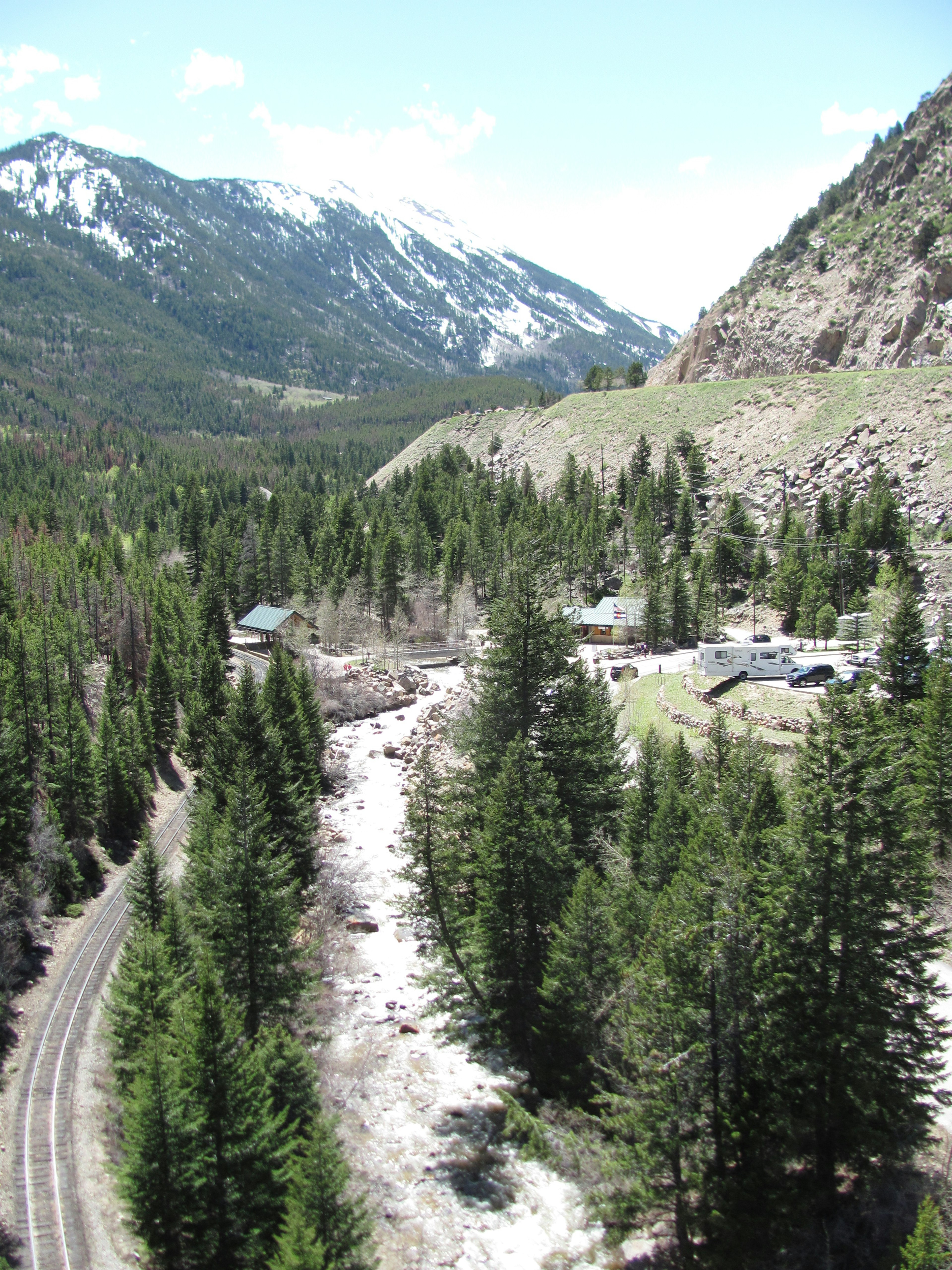 A scenic view of a small village surrounded by mountains and forests with a river