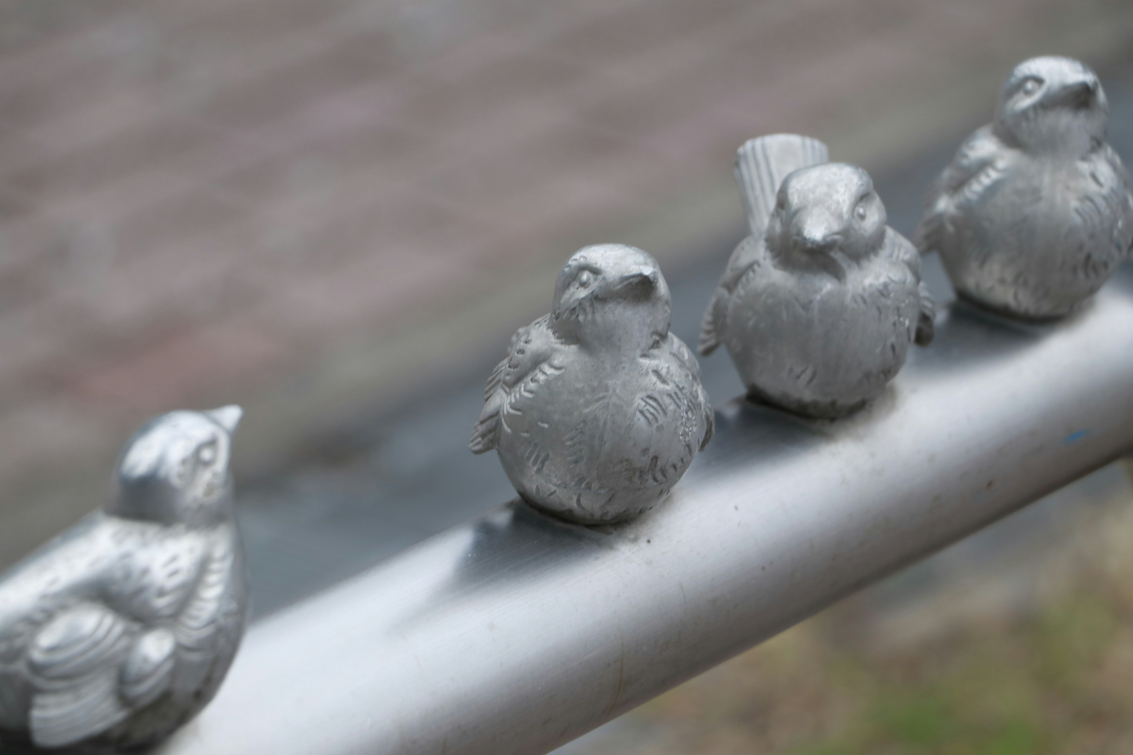 Four silver bird sculptures lined up on a railing