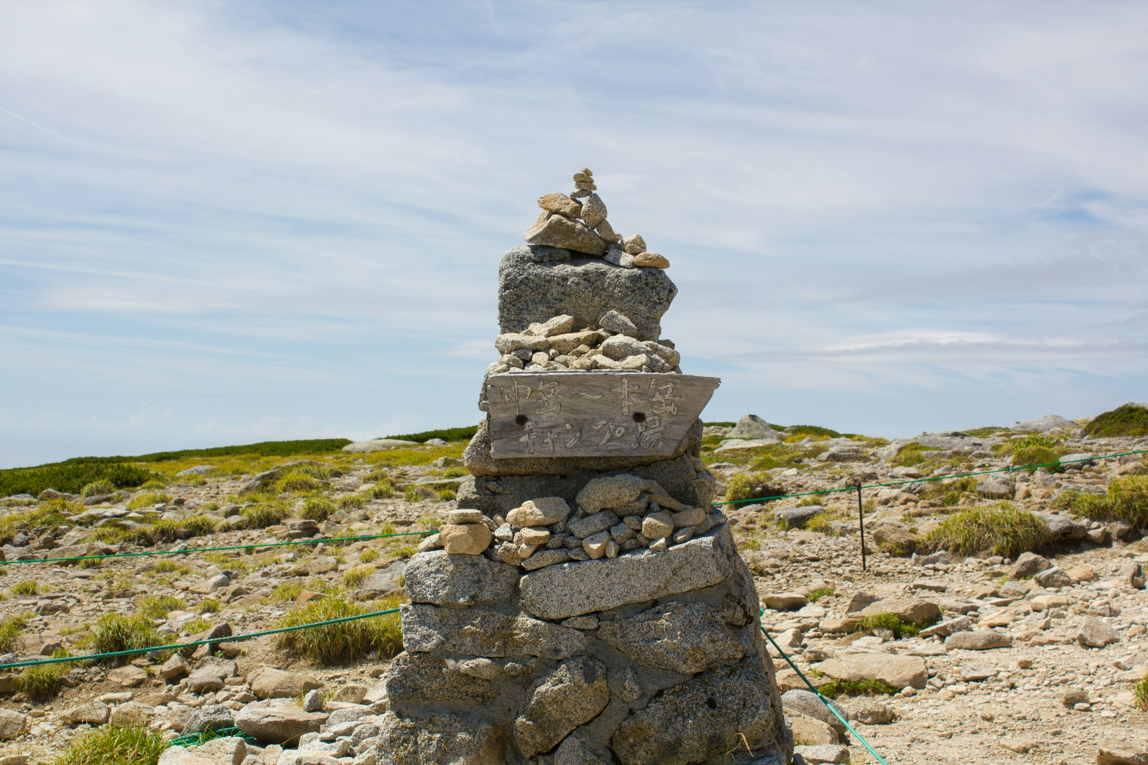 A stone cairn stands under a blue sky