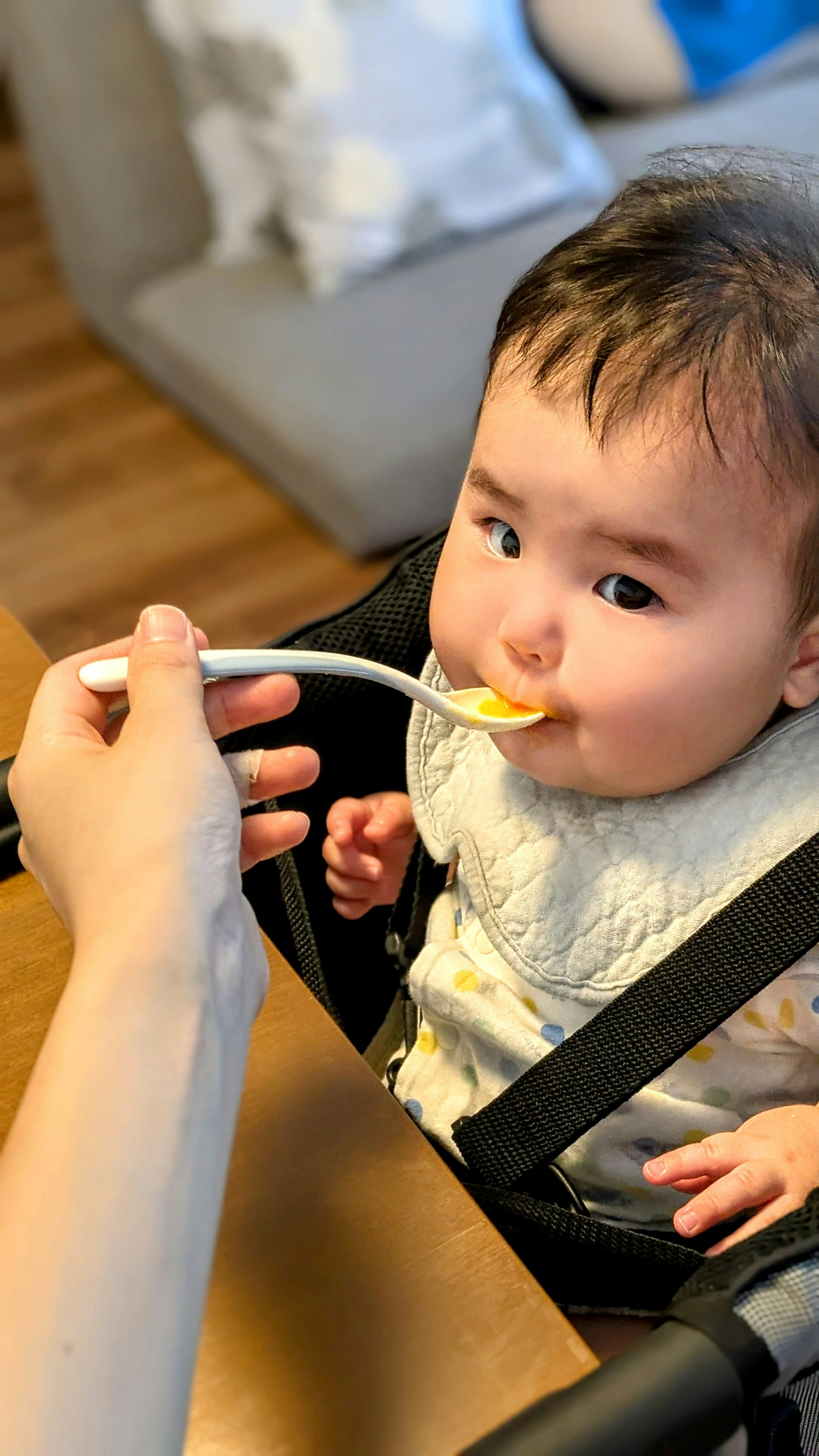 Baby eating from a spoon with a caregiver feeding