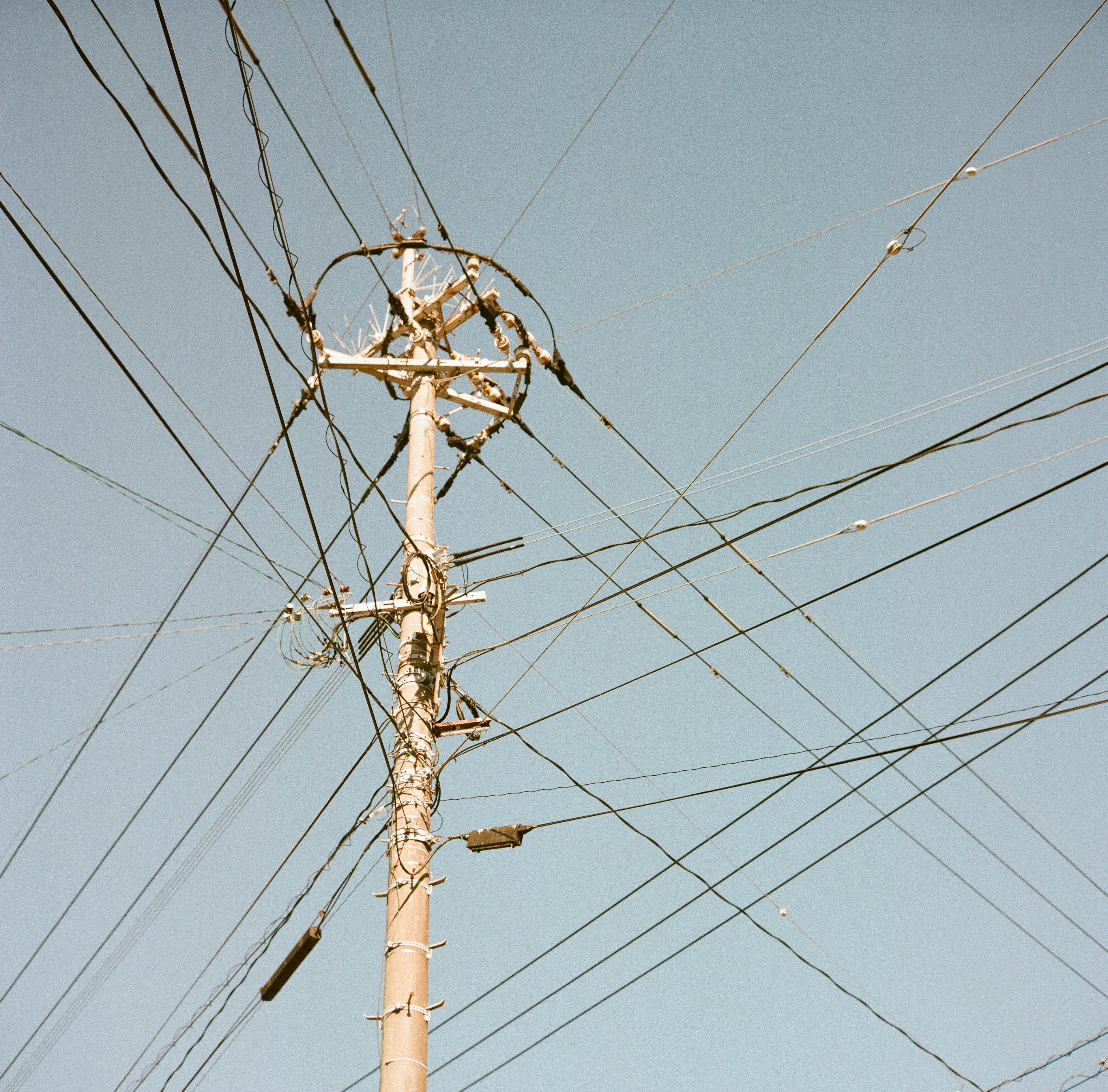 Strommast mit einem komplexen Netzwerk von Drähten vor blauem Himmel