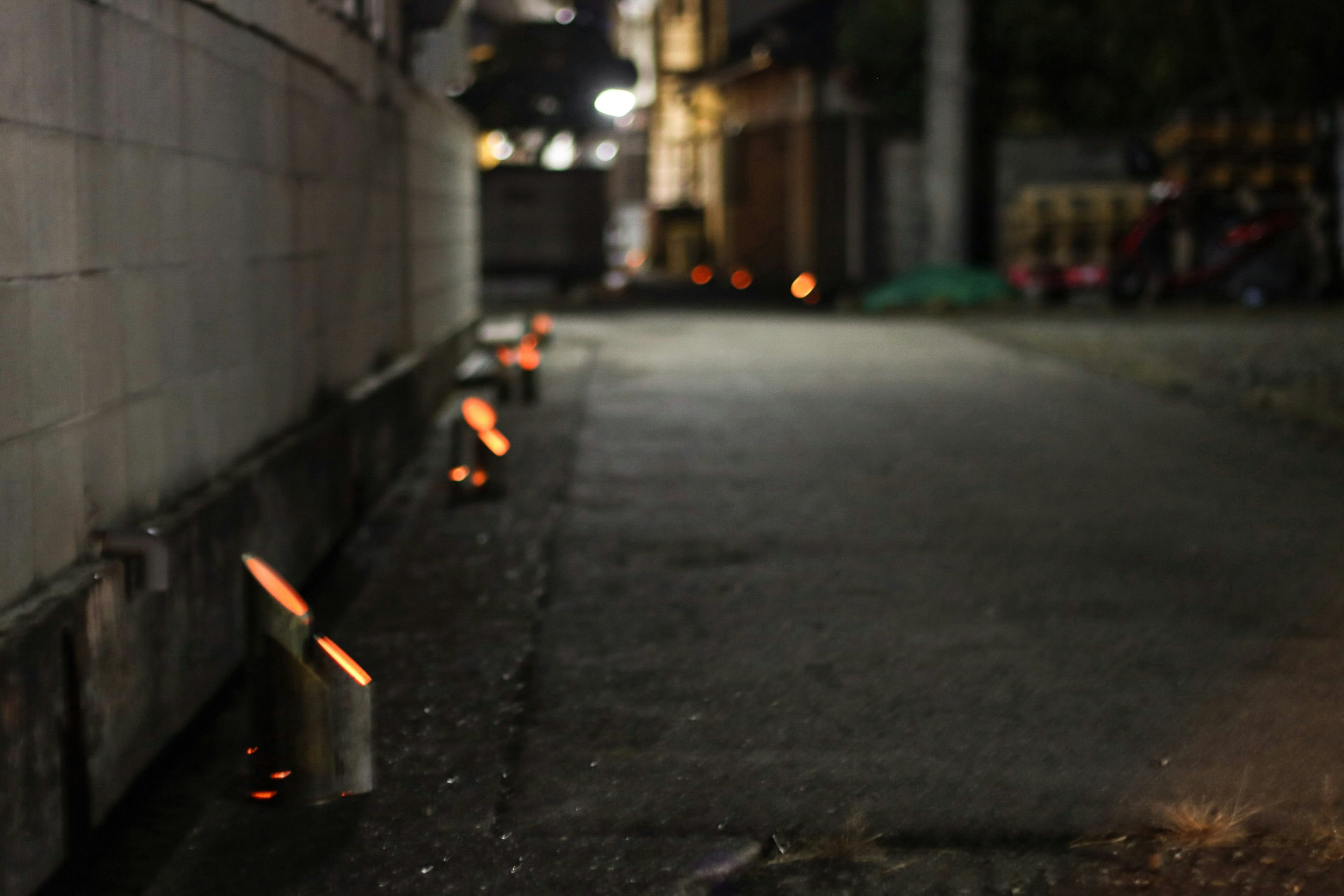 Pequeñas llamas alineadas en un callejón oscuro por la noche con sombras de pared