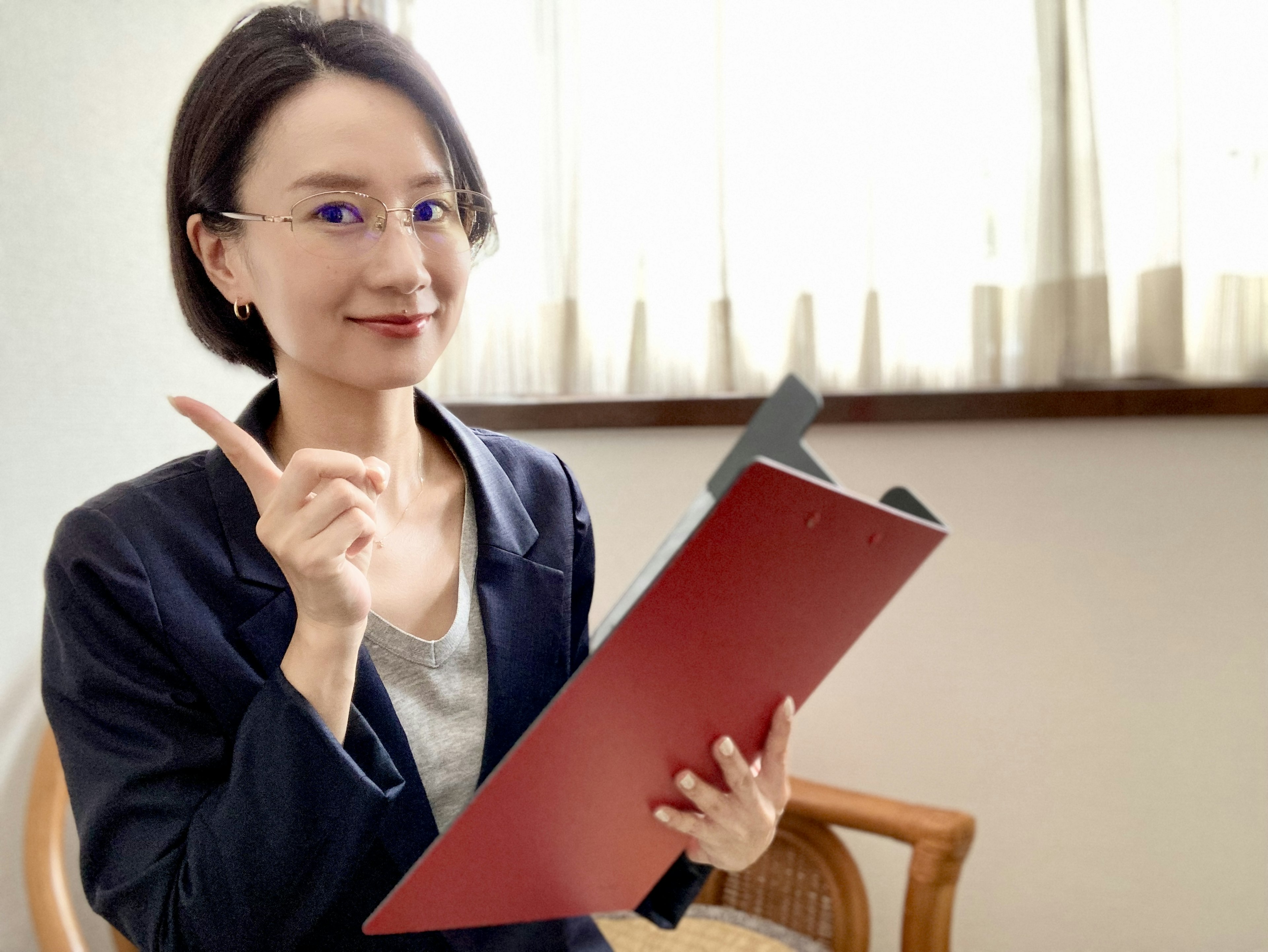 A woman in a business setting holding a red folder and pointing