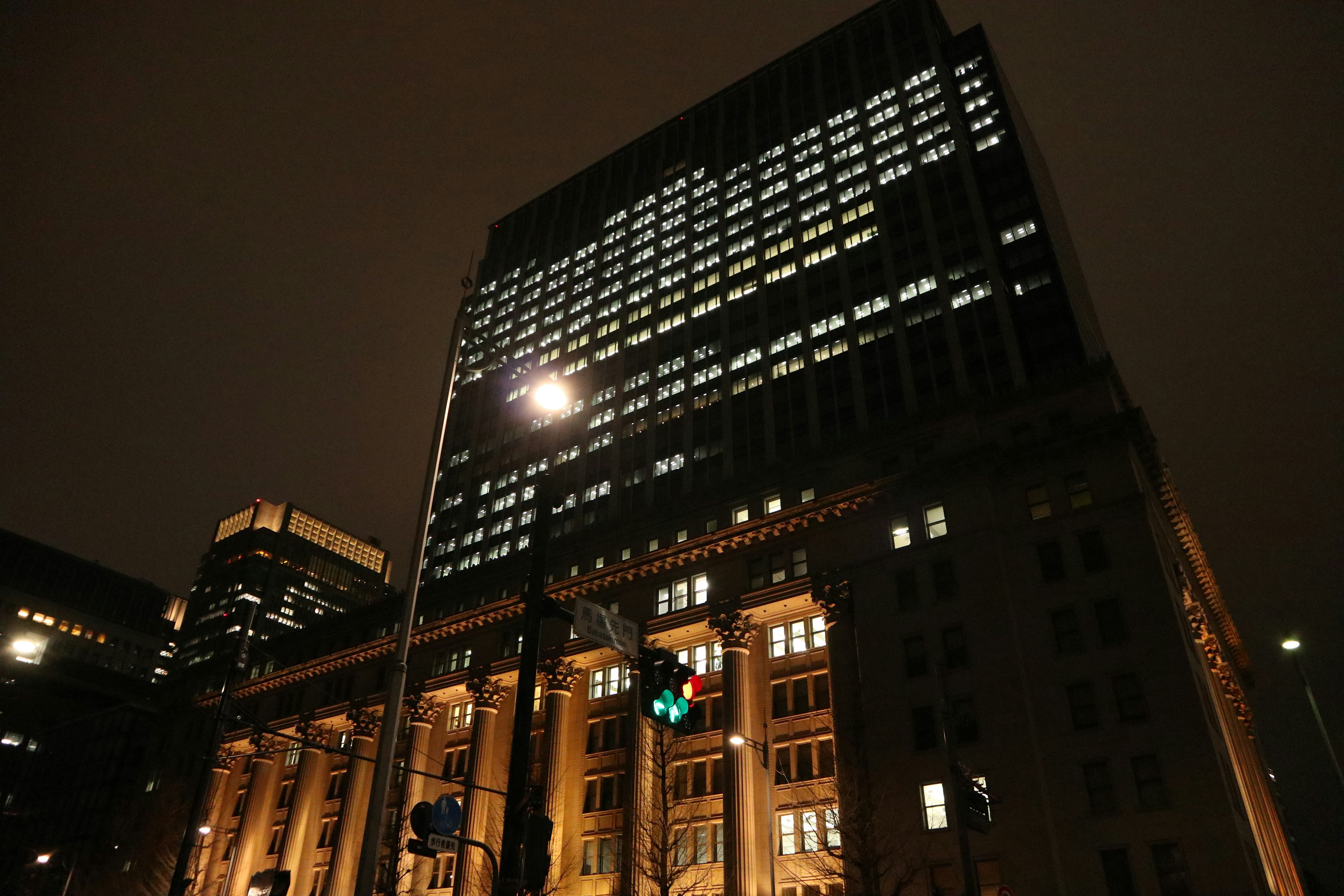 Night cityscape featuring a tall building with illuminated windows and street lights