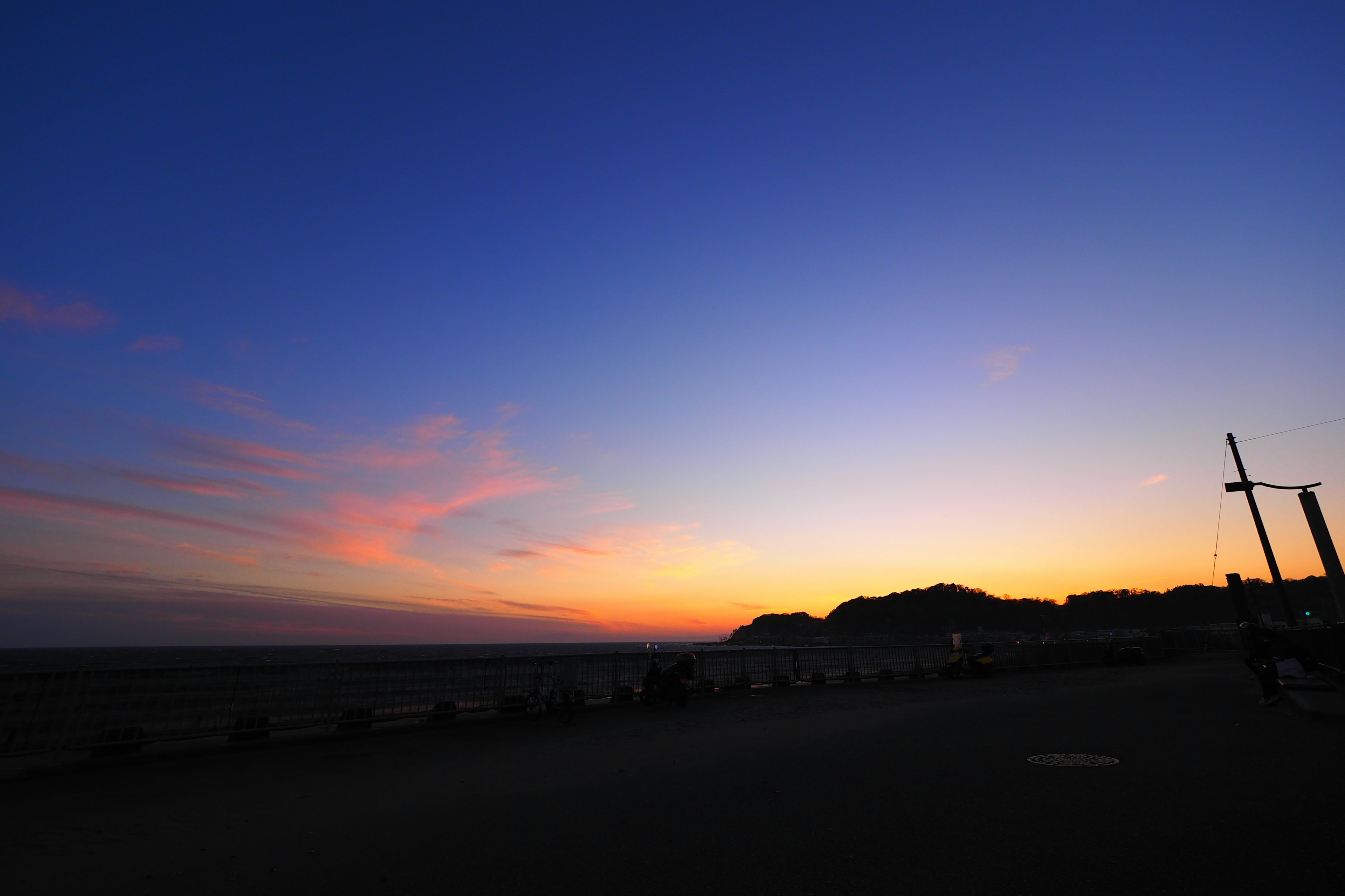 Pemandangan matahari terbenam di pantai dengan warna langit yang cerah