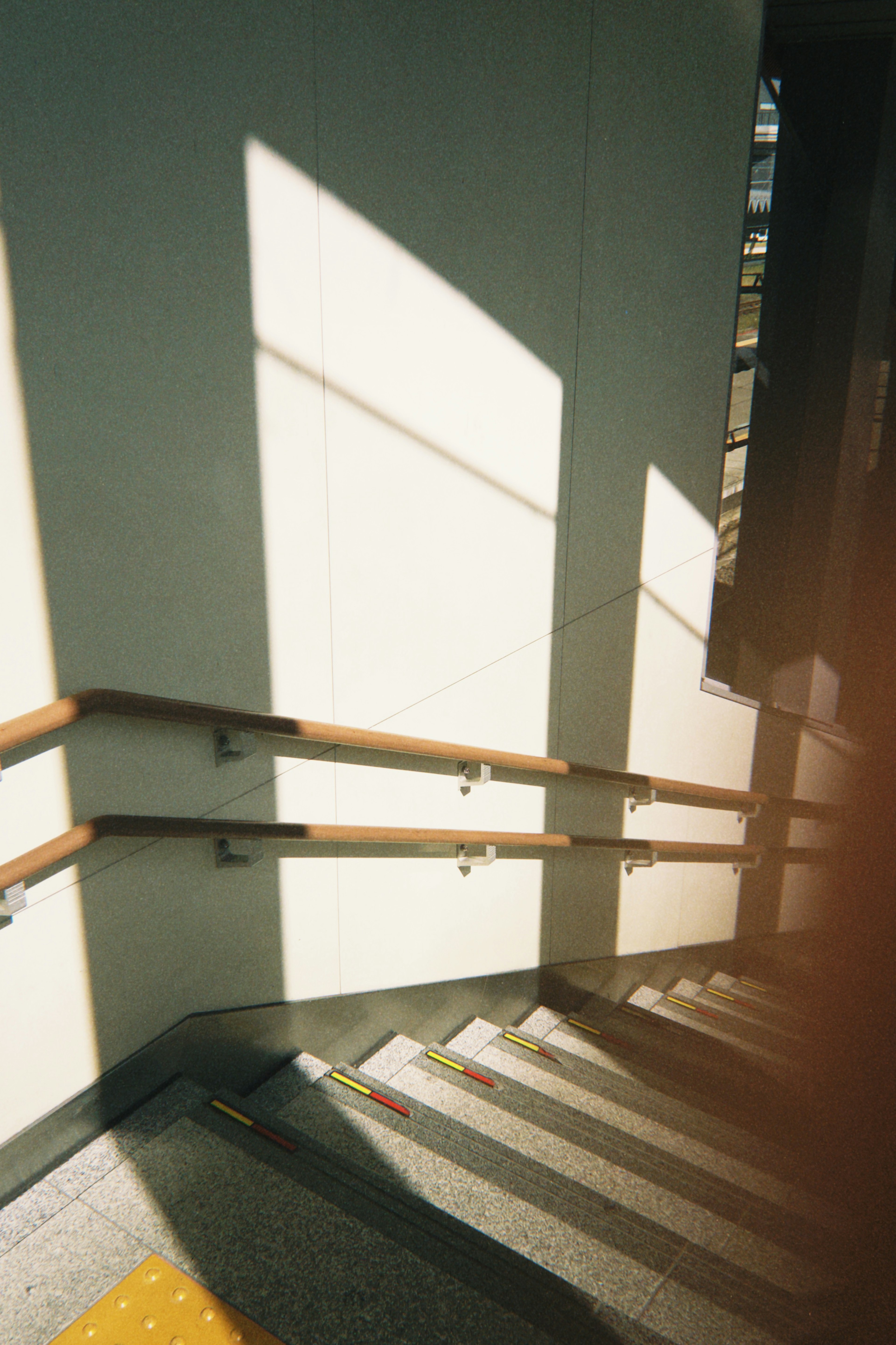 Vista interior de escaleras con barandillas de madera y sombras llamativas