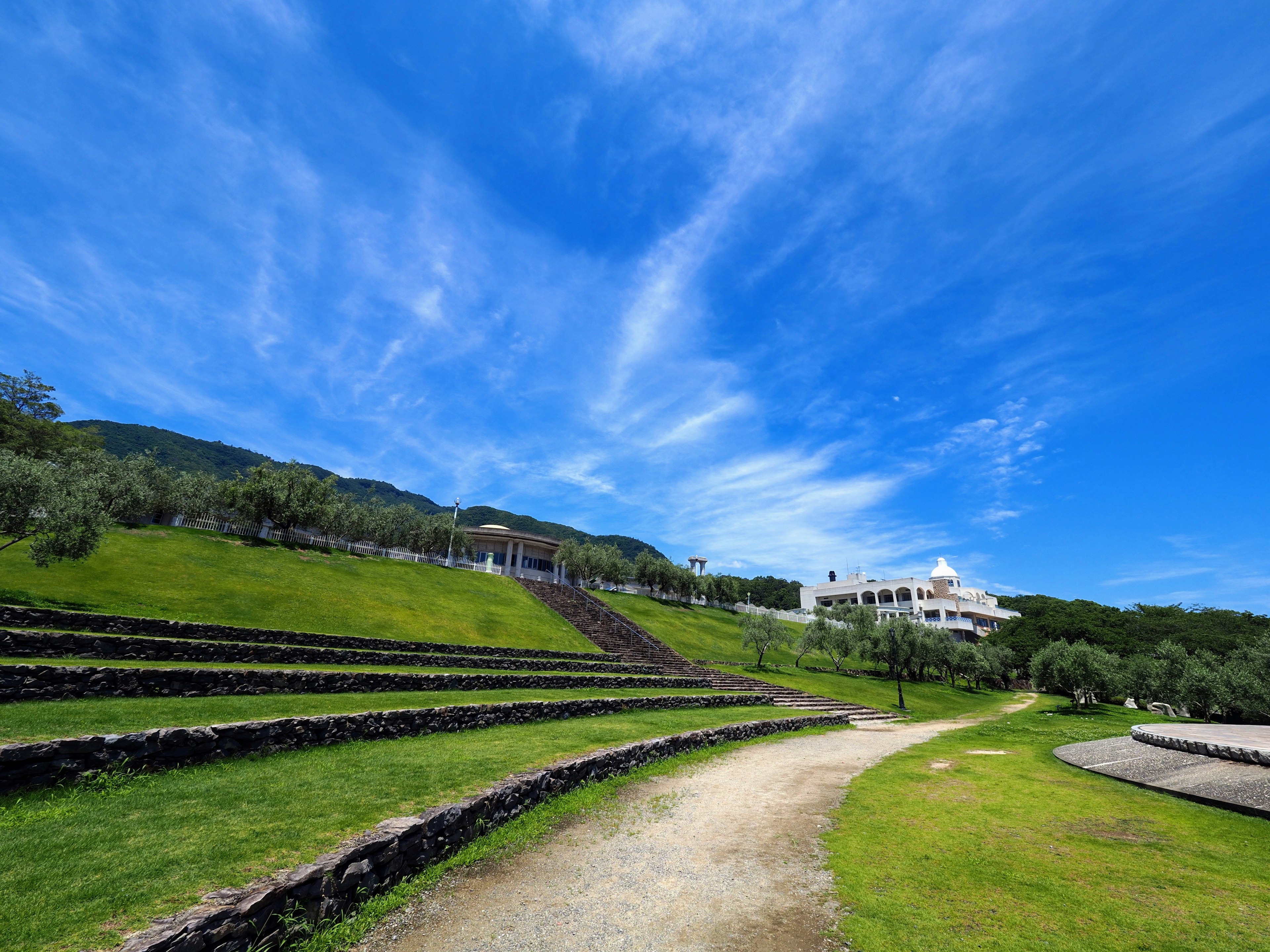 Vista escénica de un camino con escalones de piedra en colinas verdes bajo un cielo azul