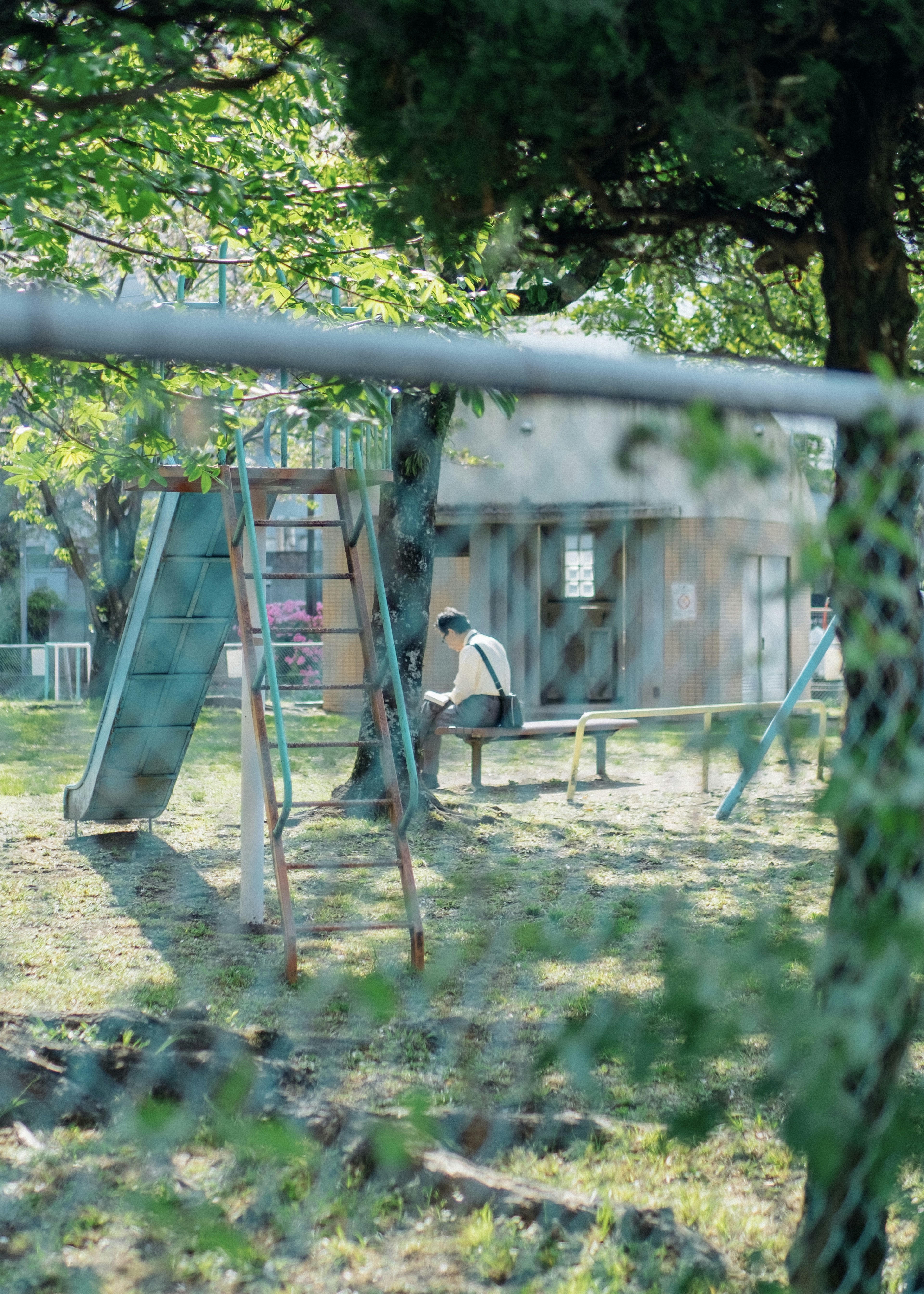 公園裡一個男孩坐在秋千旁的長椅上