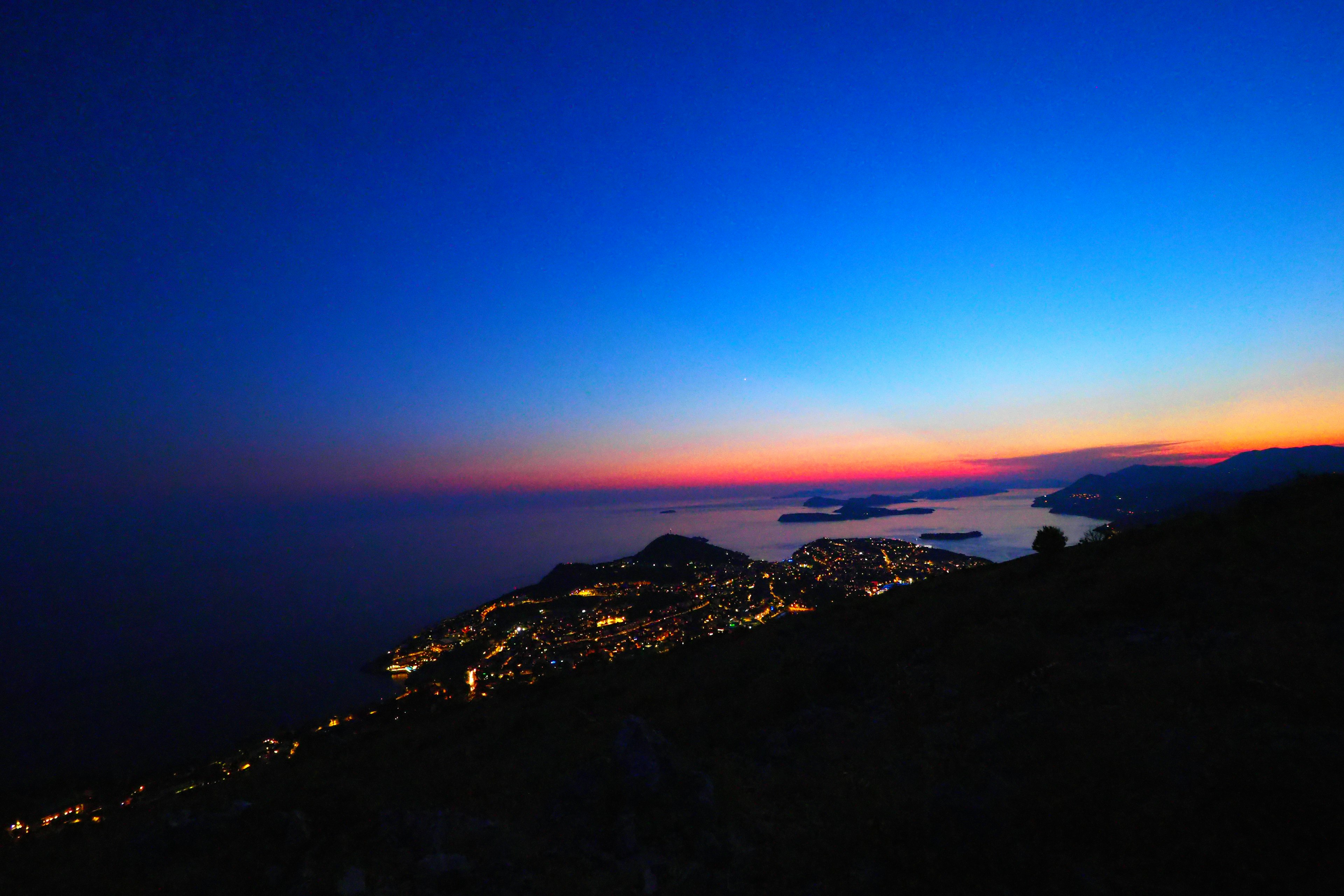 Atardecer azul sobre el mar con luces de la ciudad brillando