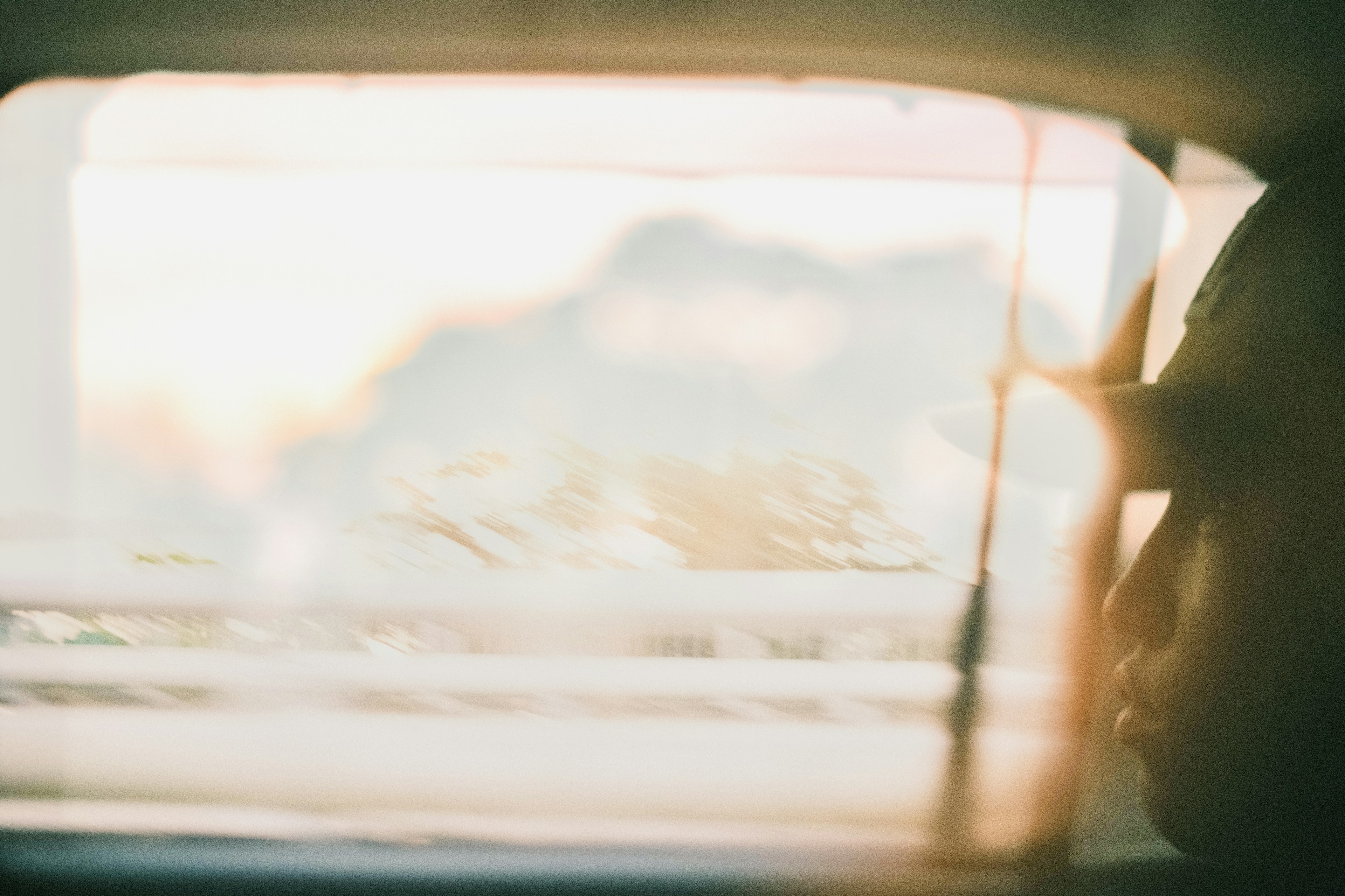 Paesaggio sfocato e silhouette di una persona vista attraverso un finestrino dell'auto